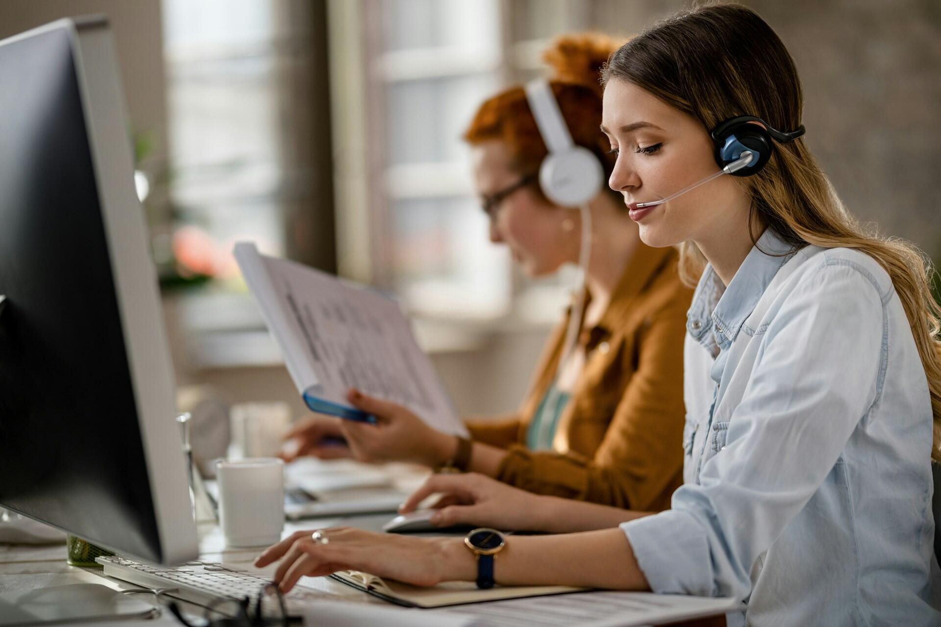 Une femme devant un ordinateur et qui porte un casque pour répondre aux appels