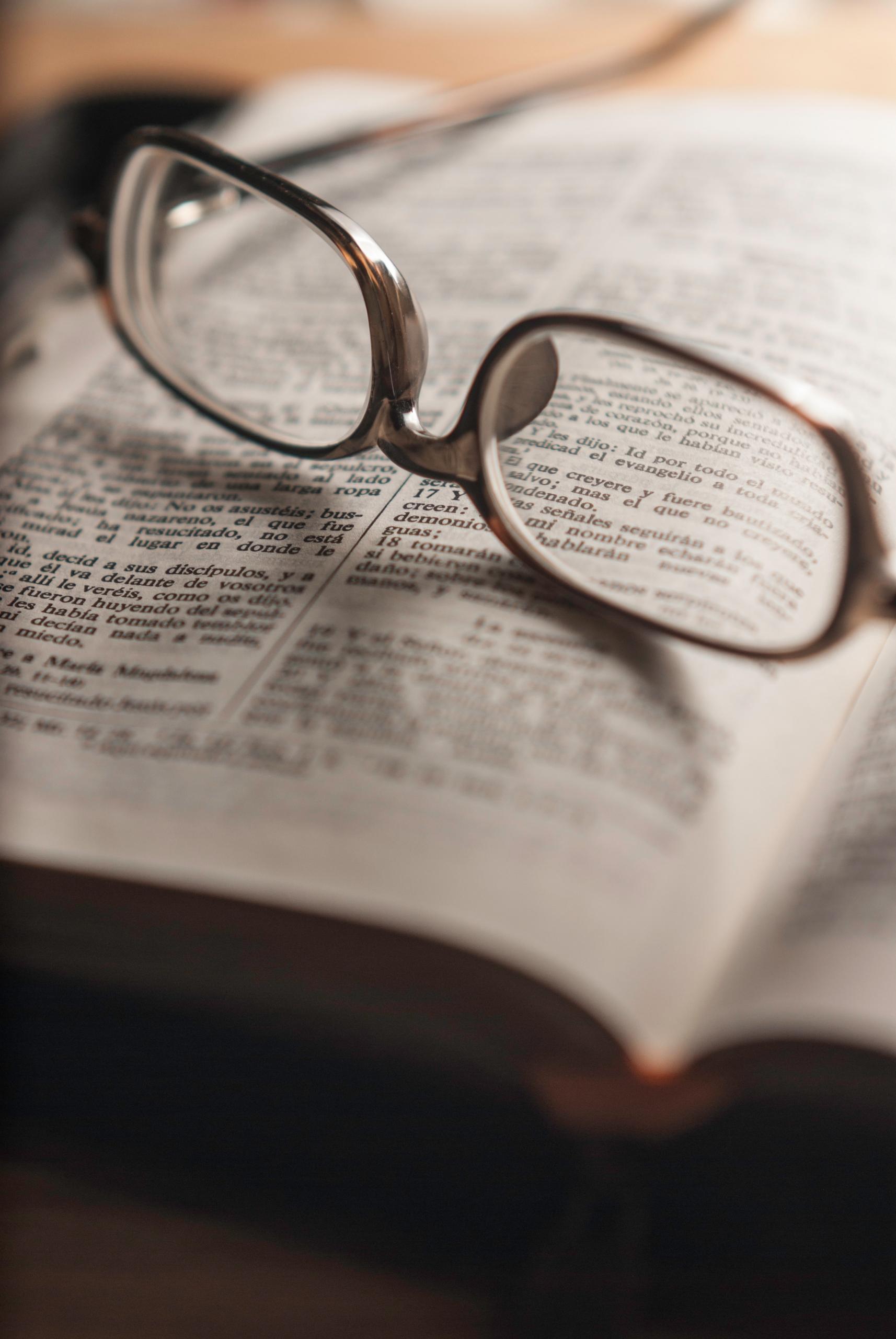 Des lunettes posées sur un livre en espagnol.