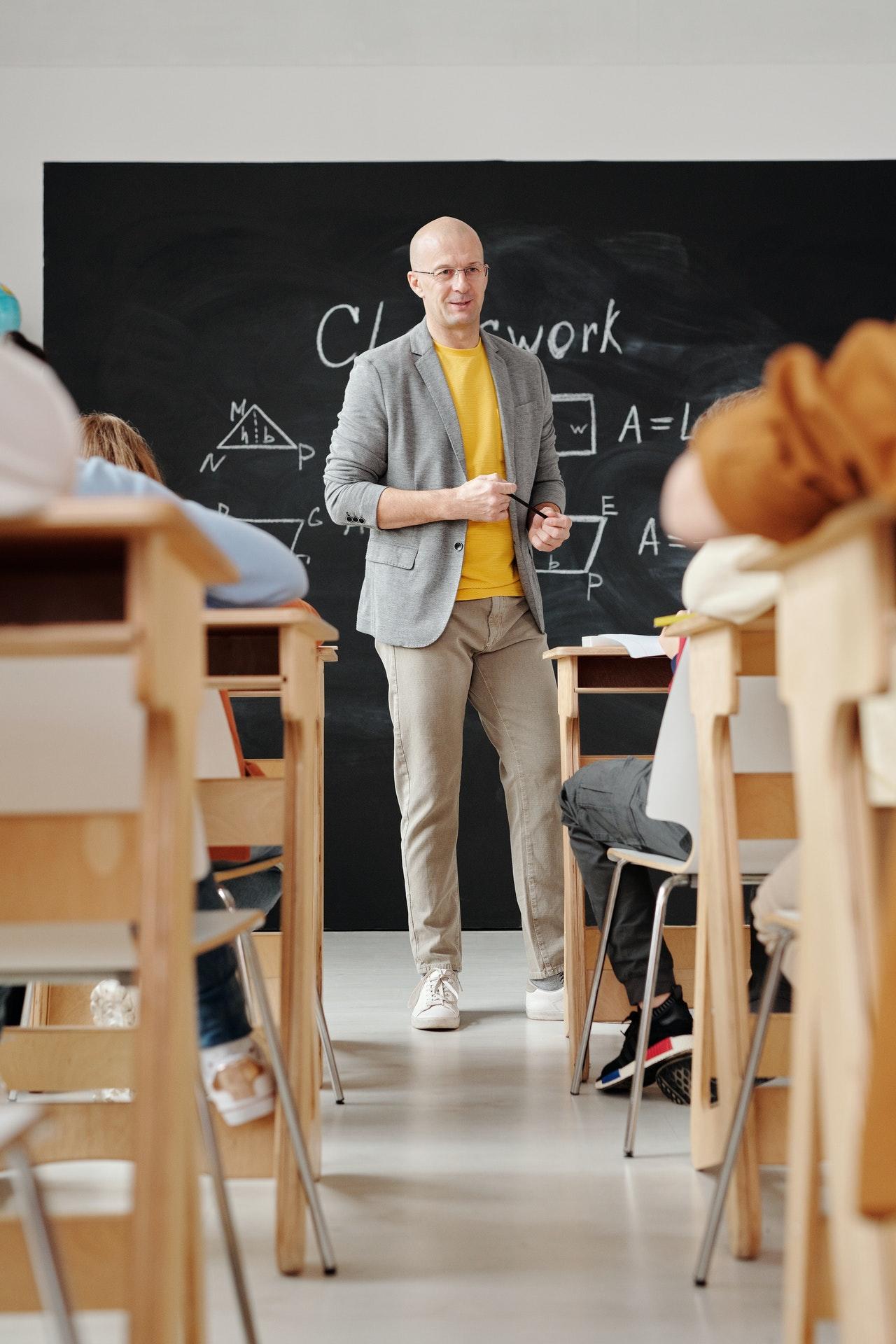 Un professeur donne cours au tableau à des collégiens.