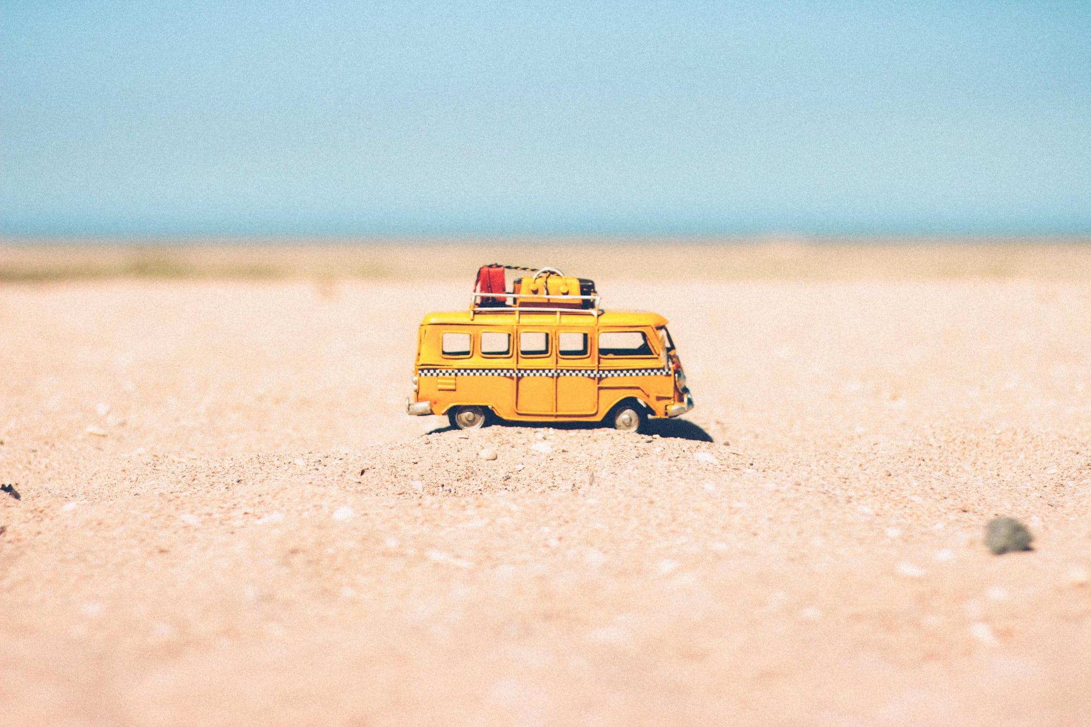 Un van de vacanciers miniature est posé sur le sable.