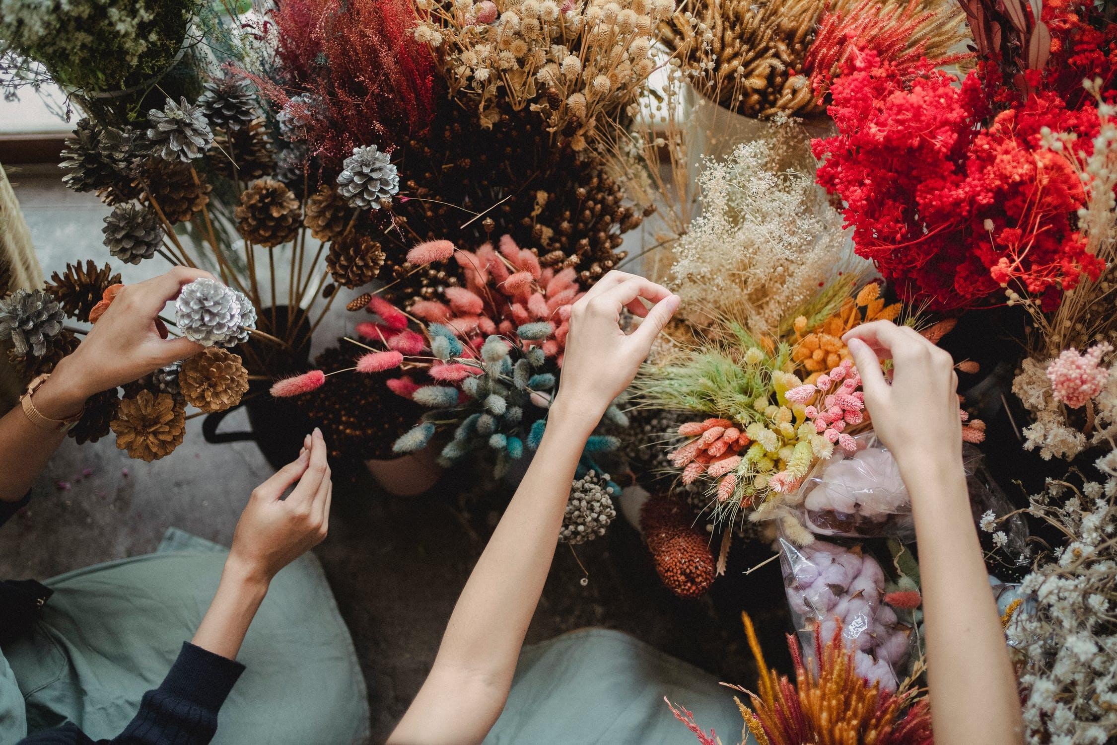 Des mains d'apprentis fleuristes sélectionnent des fleurs.