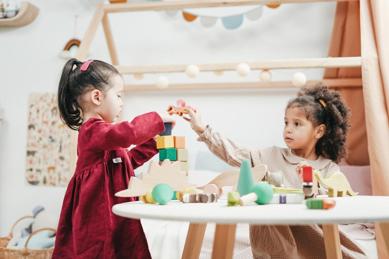 Deux petites filles qui jouent à empiler des cubes sur une table.
