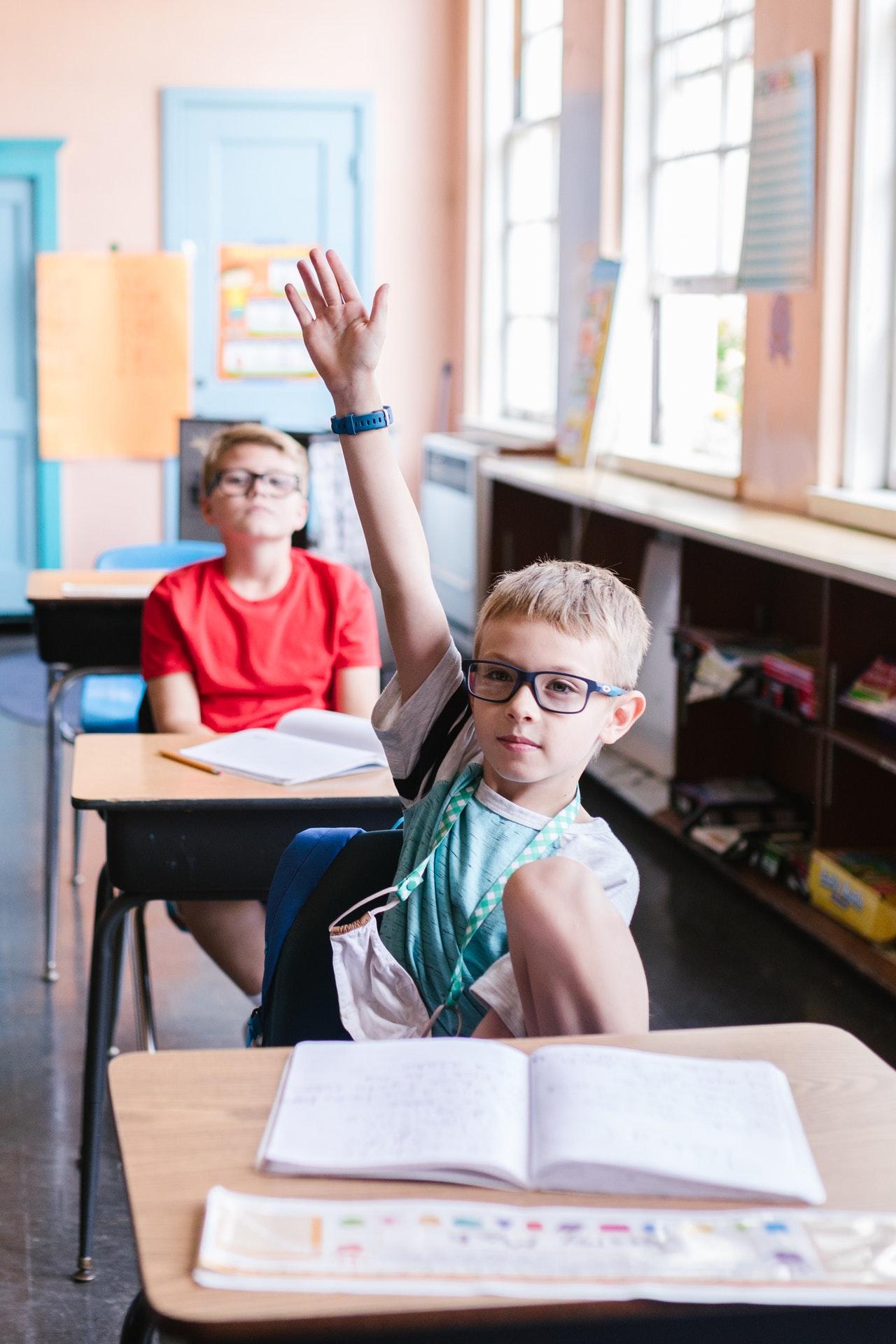 Enfant qui lève la main dans une salle de classe.