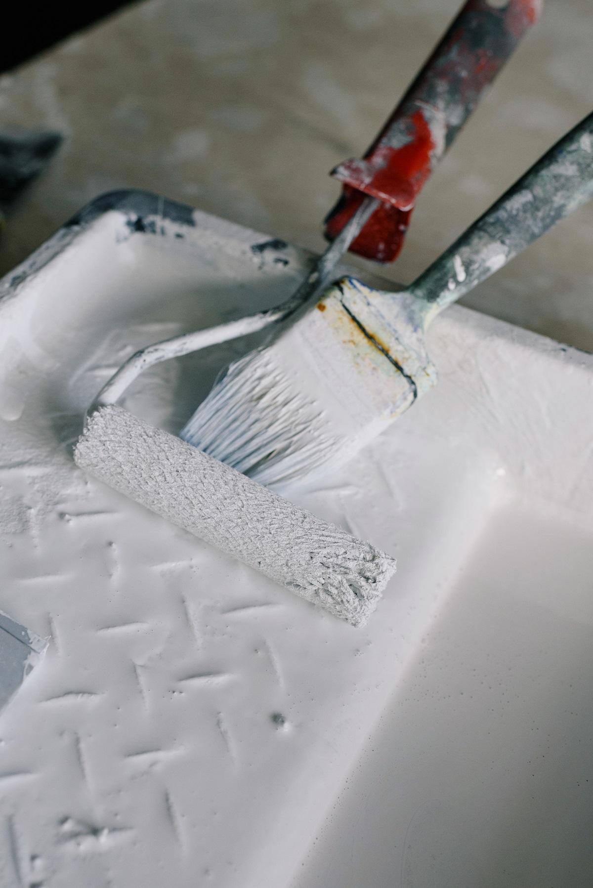 Des pinceaux sont posés dans de la peinture blanche.