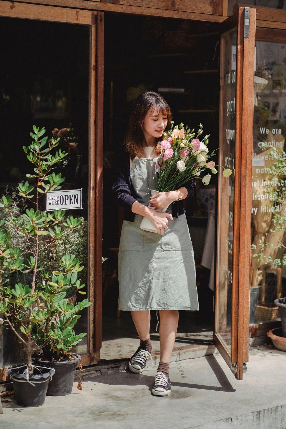 Une fleuriste en apprentissage tient un bouquet de fleurs.
