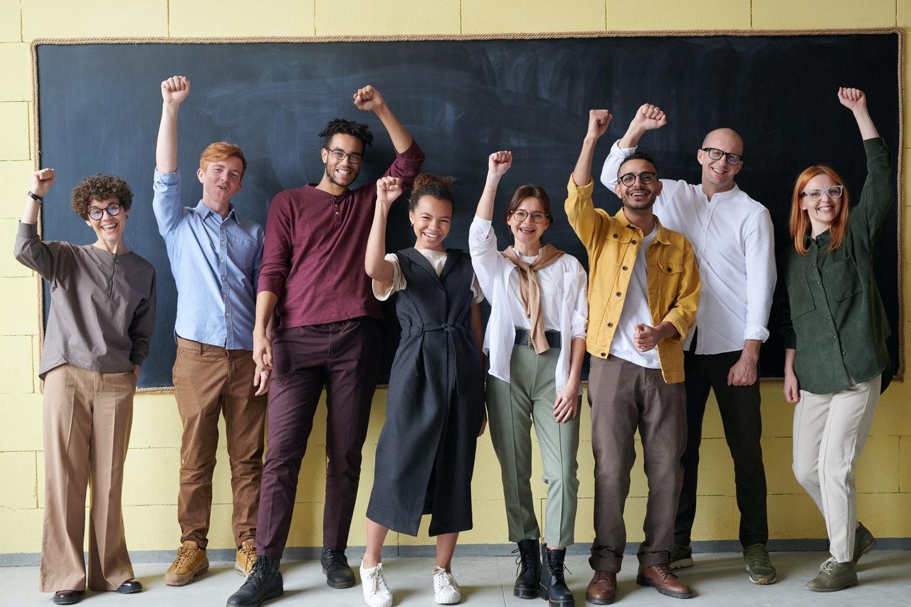 Plusieurs hommes et femmes devant le tableau noir d'une école ou d'un collège.