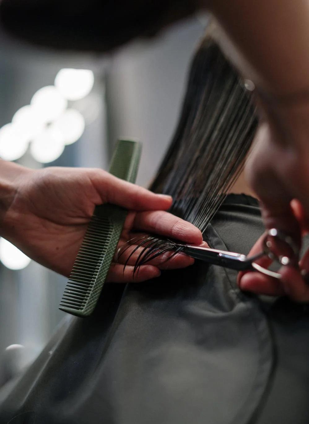 Un coiffeur en apprentissage coupe des cheveux.