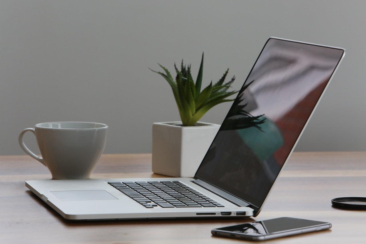 Macbook ouvert sur une table avec un iphone à côté. 