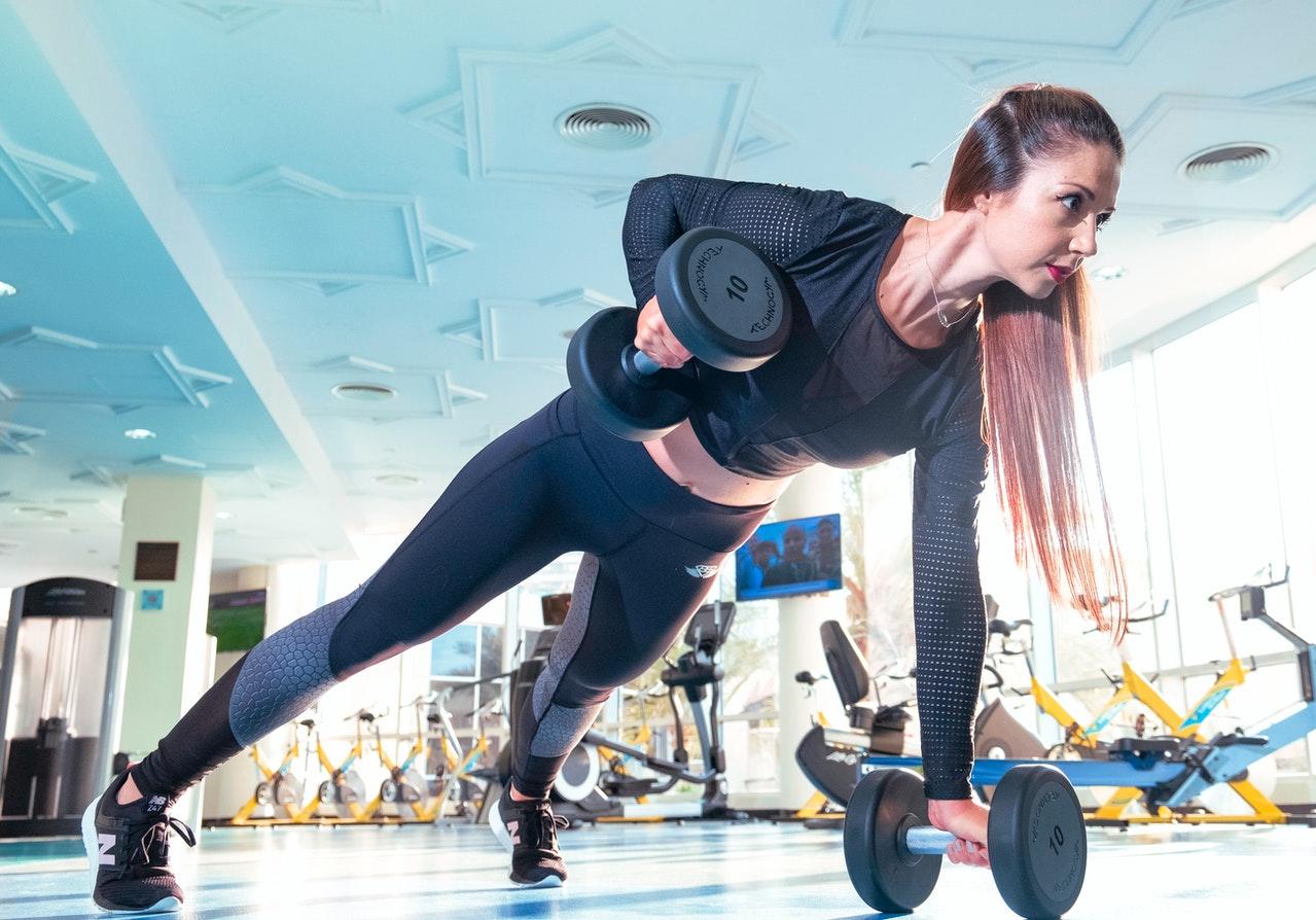 Jeune femme en gainage soulevant un poids.