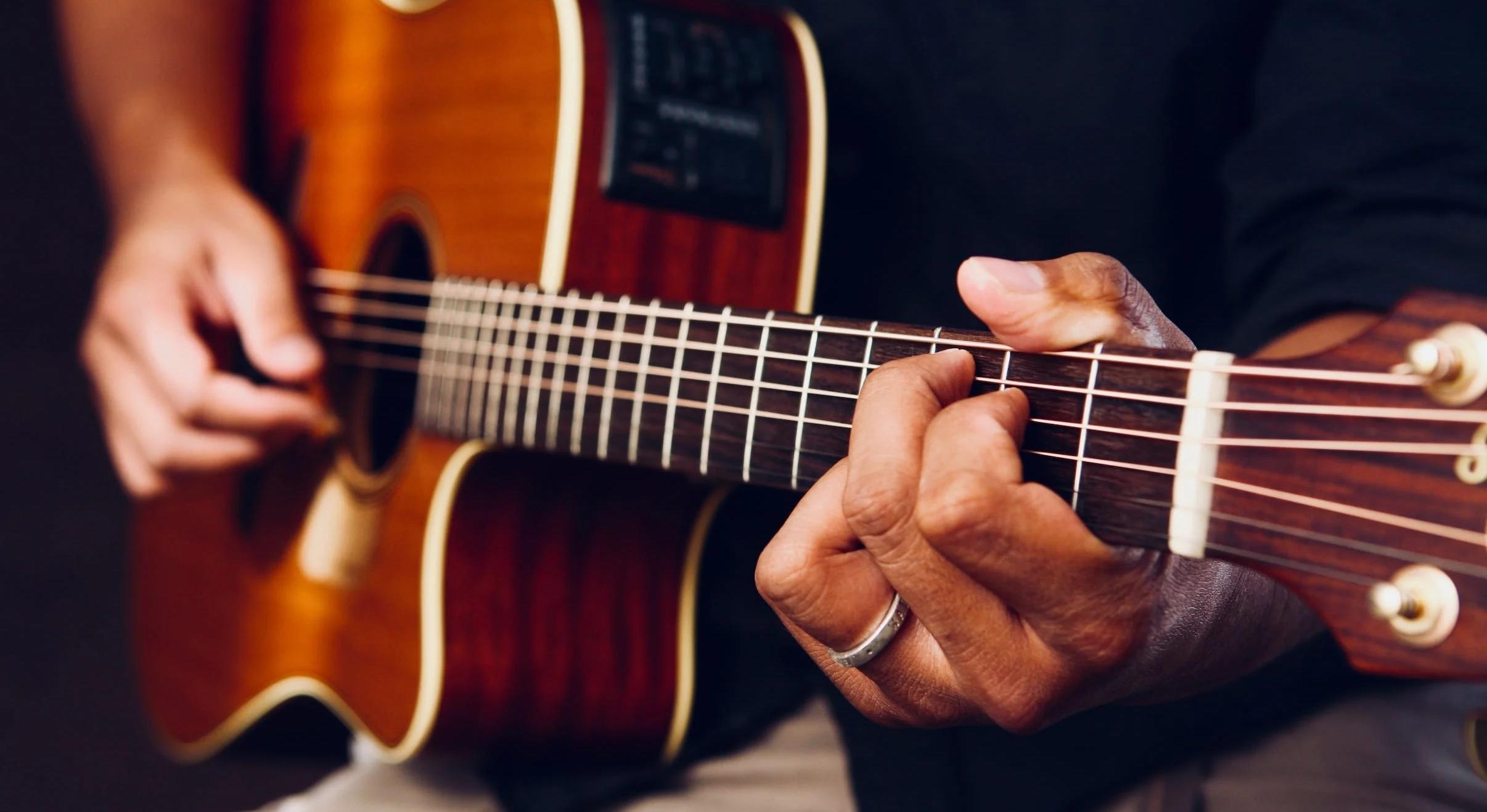 Une personne joue de la guitare electro-acoustique.