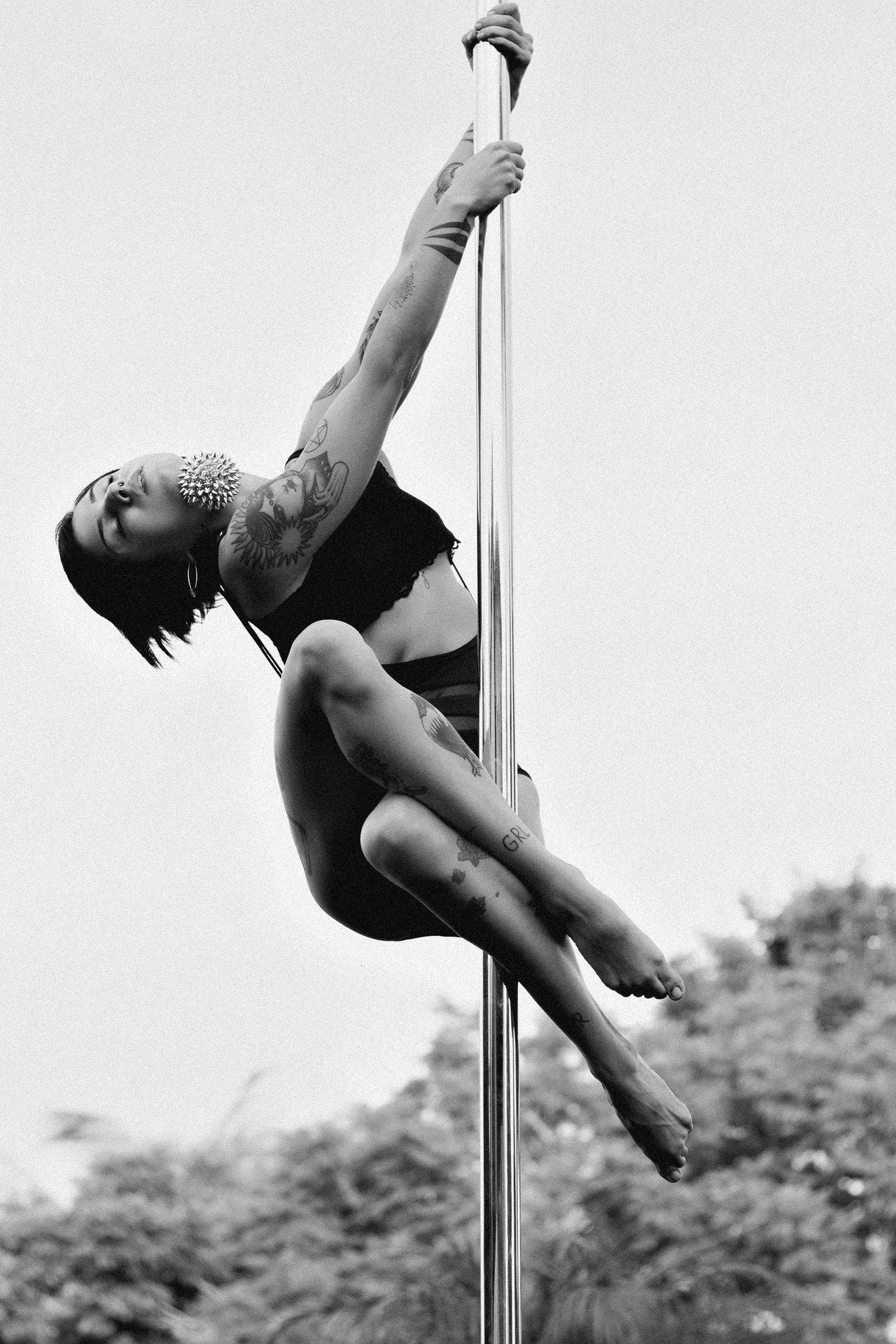 Jeune femme tatouée faisant de la pole dance.
