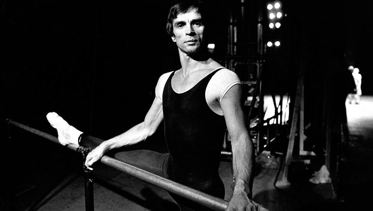 Rudolf Noureev avec la jambe tendue sur une barre.