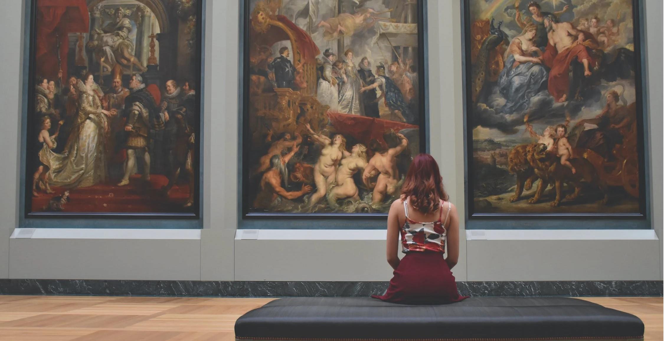Une femme admire des tableaux dans un musée.