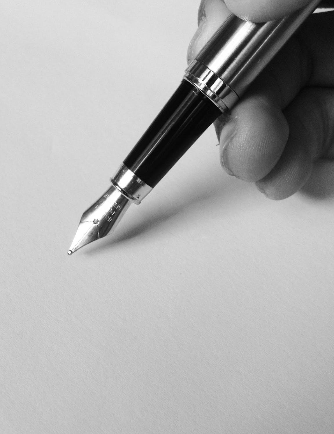 Un stylo plume est tenu par une main.