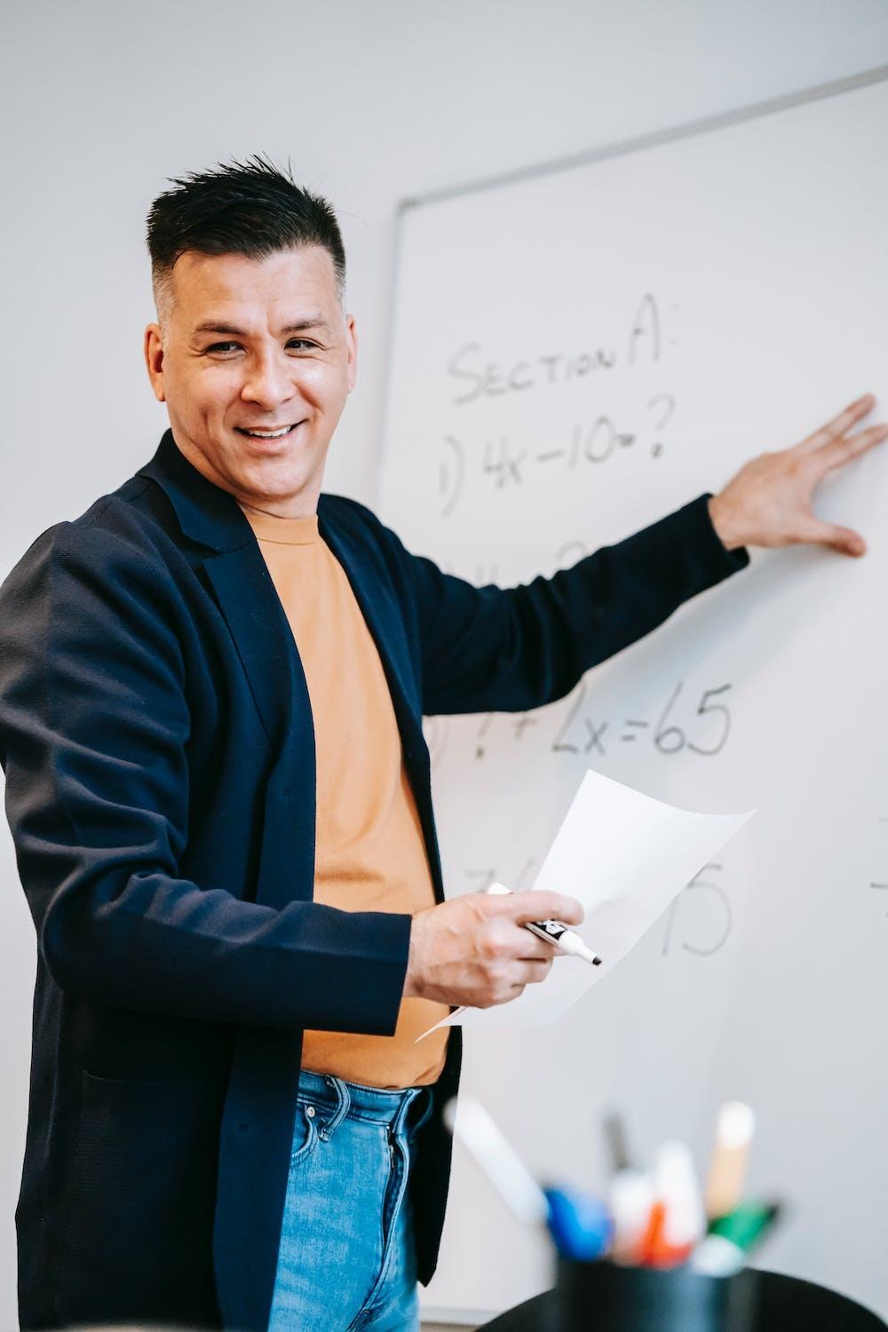 Un professeur donne cours devant son tableau.