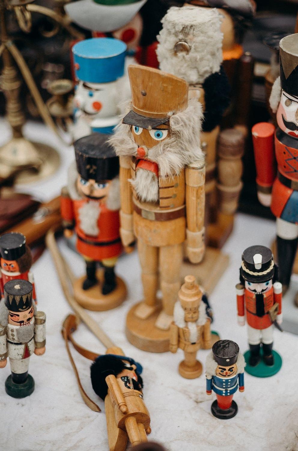 Des personnages en bois sont disposés sur une table de marché de noël.