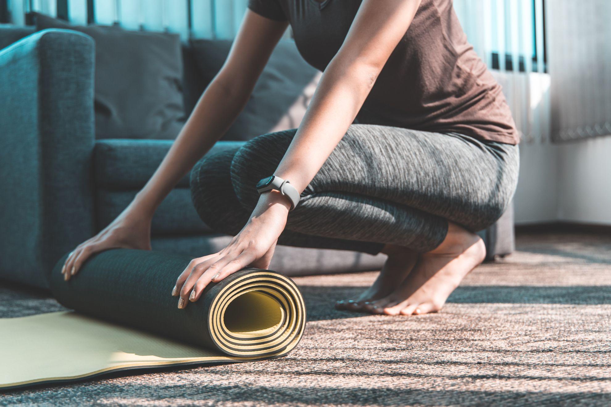 Une femme en train d'enrouler son tapis de yoga.