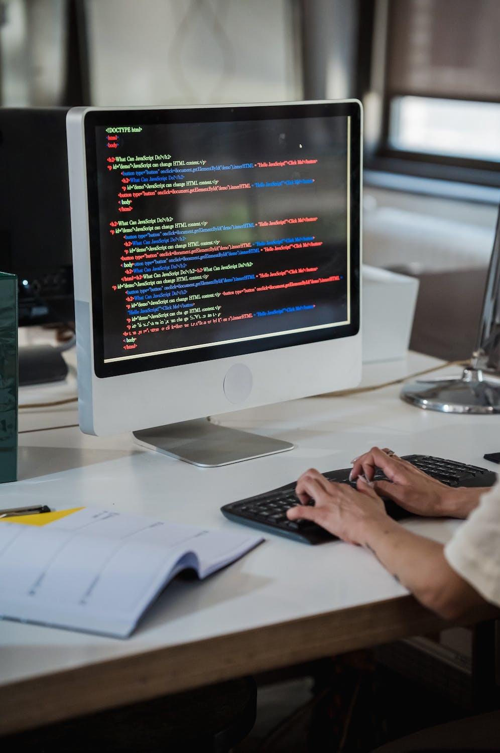 Une personne écrit un code informatique sur son ordinateur.