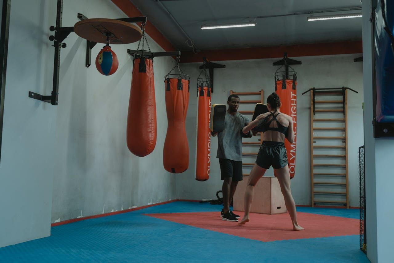 Jeune femme s'entraînant avec un coach de boxe dans une salle.