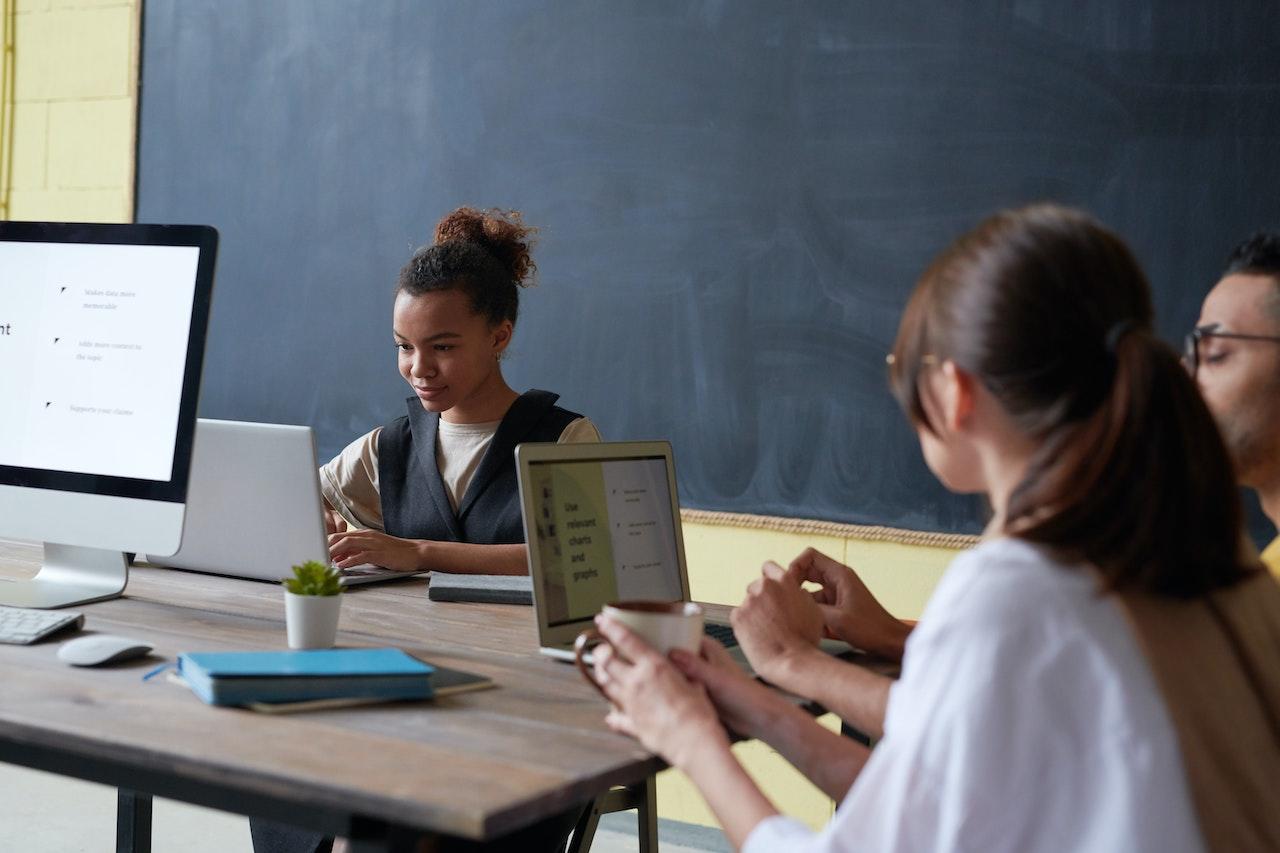 Des élèves sont devant des ordinateurs pour préparer un atelier dans une salle de classe.
