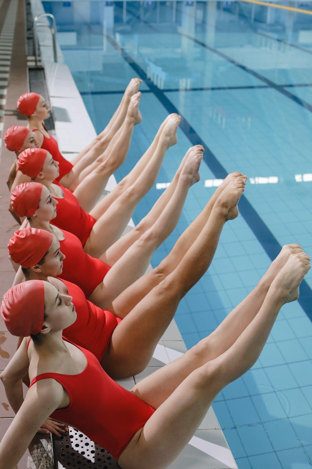 Des nageuses de natation synchronisée se trouvent au bord de la piscine.