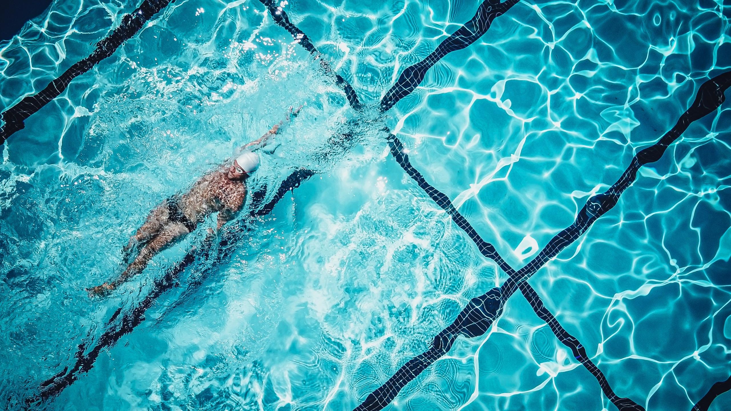 nageur avec lunettes et maillot de bain sur le dos dans une piscine