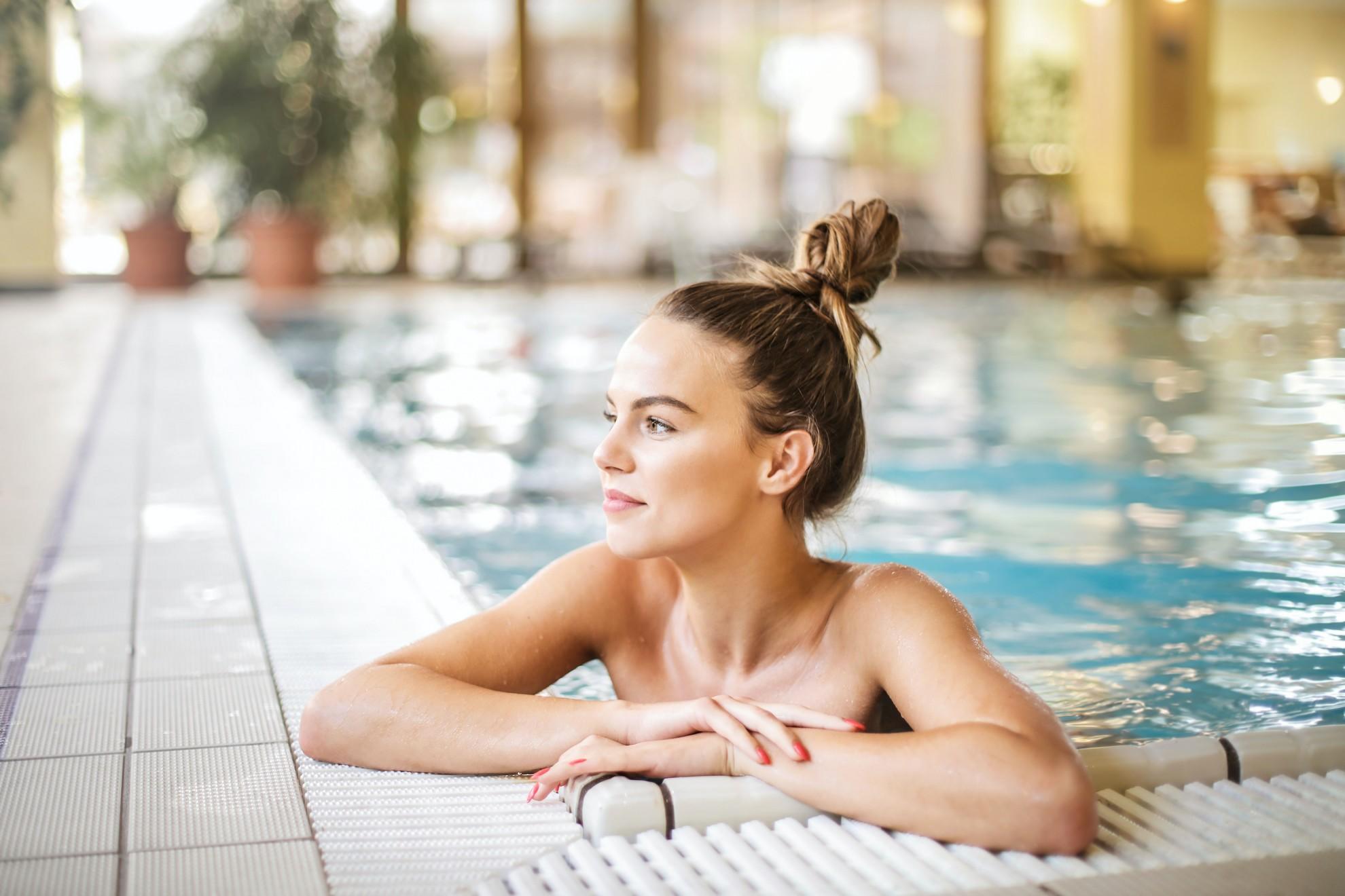 Une jeune femme accoudée sur la bordure d'une piscine.