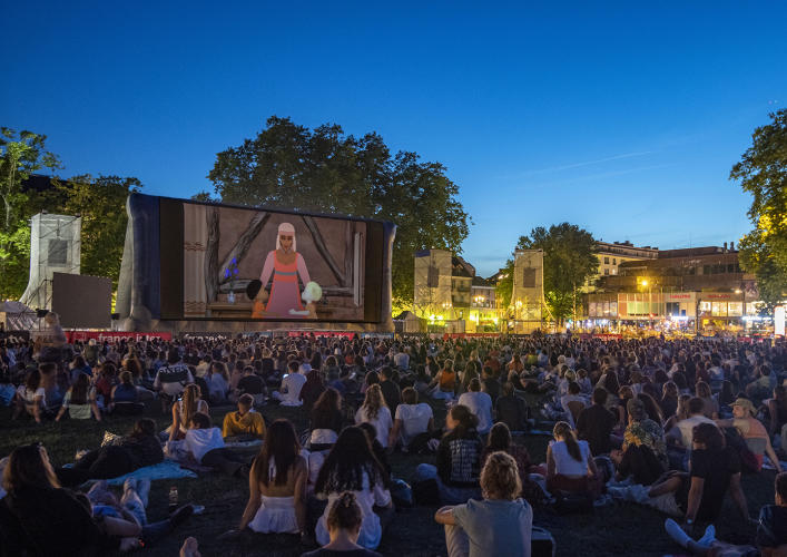 Des spectateurs regardent un dessin animé en plein air.
