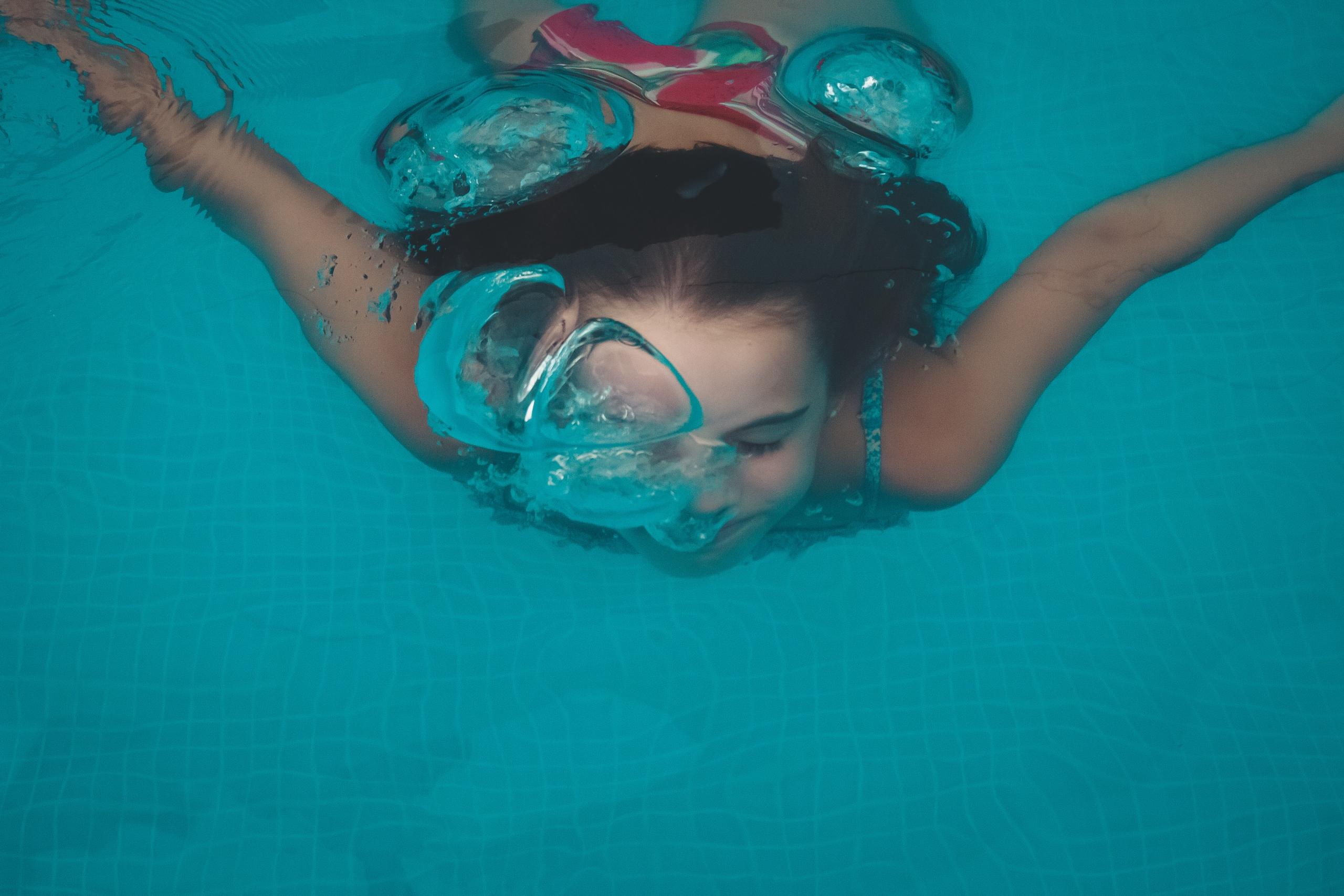 jeune fille qui nage dans la piscine et faisant une respiration avec des bulles