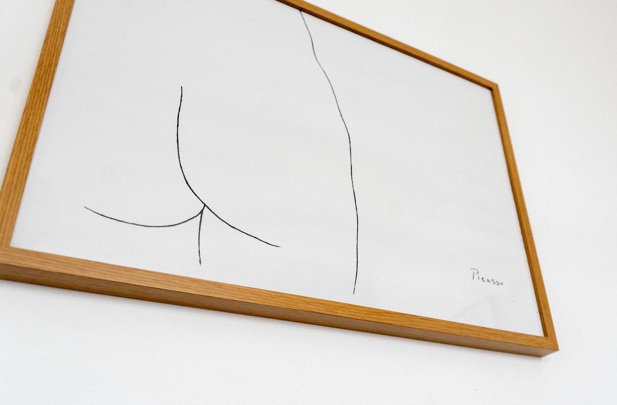 Dessin de fesses de Picasso dans un cadre sur un mur blanc. 