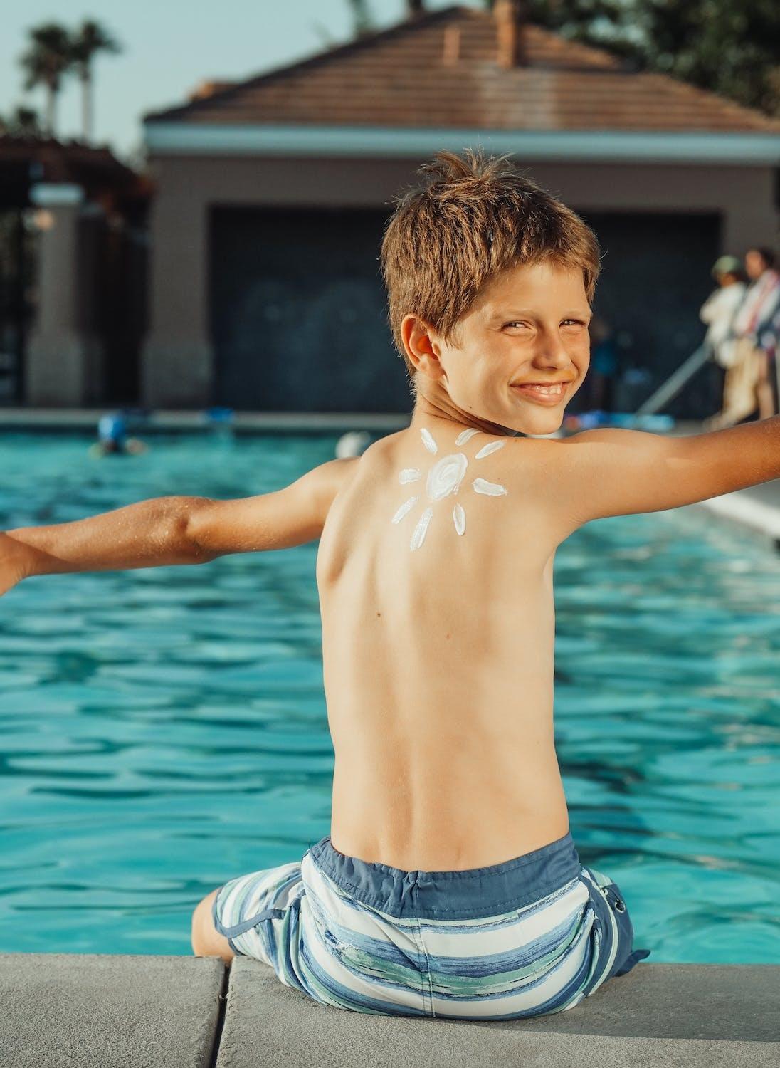 Un ado est assis en bord de piscine.