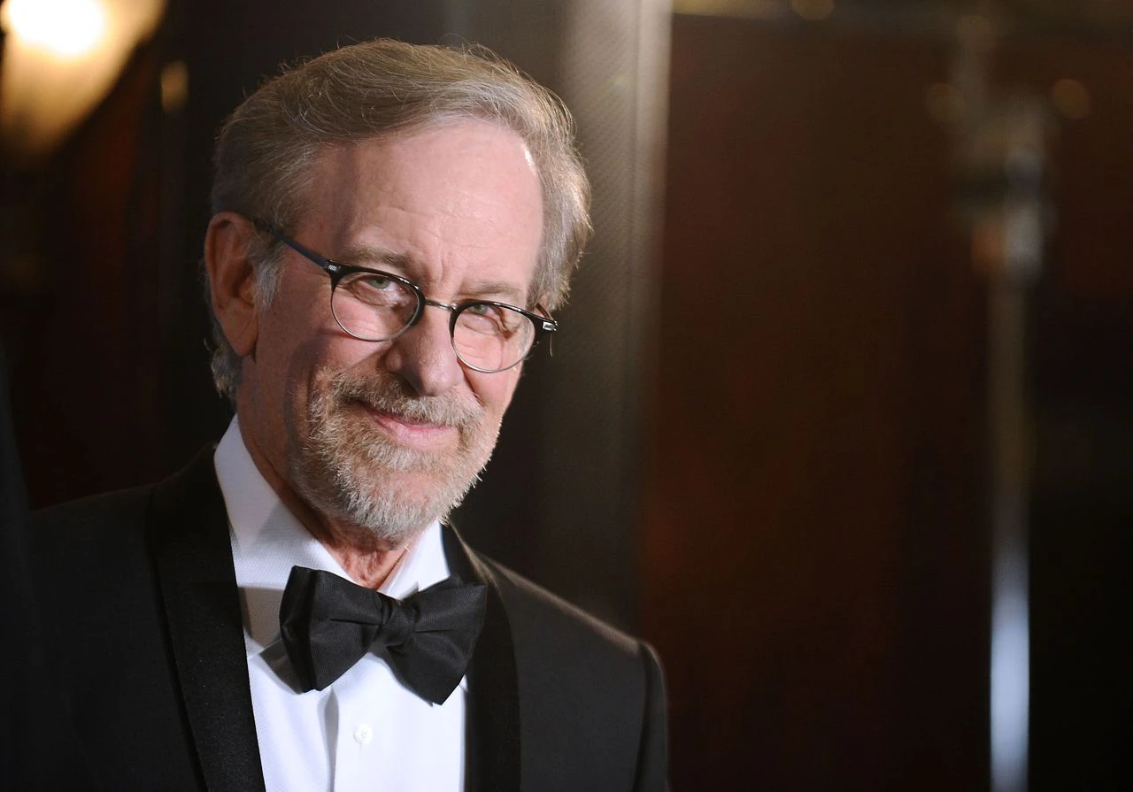 Steven Spielberg souriant, en costume noir avec un noeud papillon.