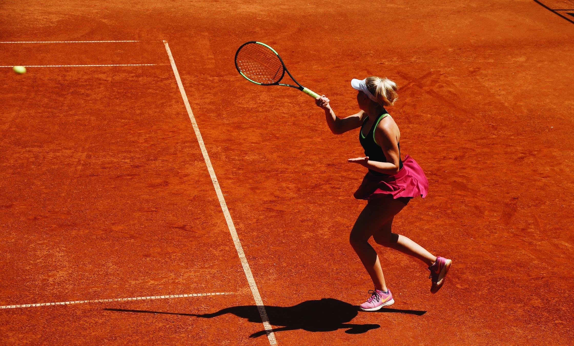Une tenniswoman est sur un court de terre battue.