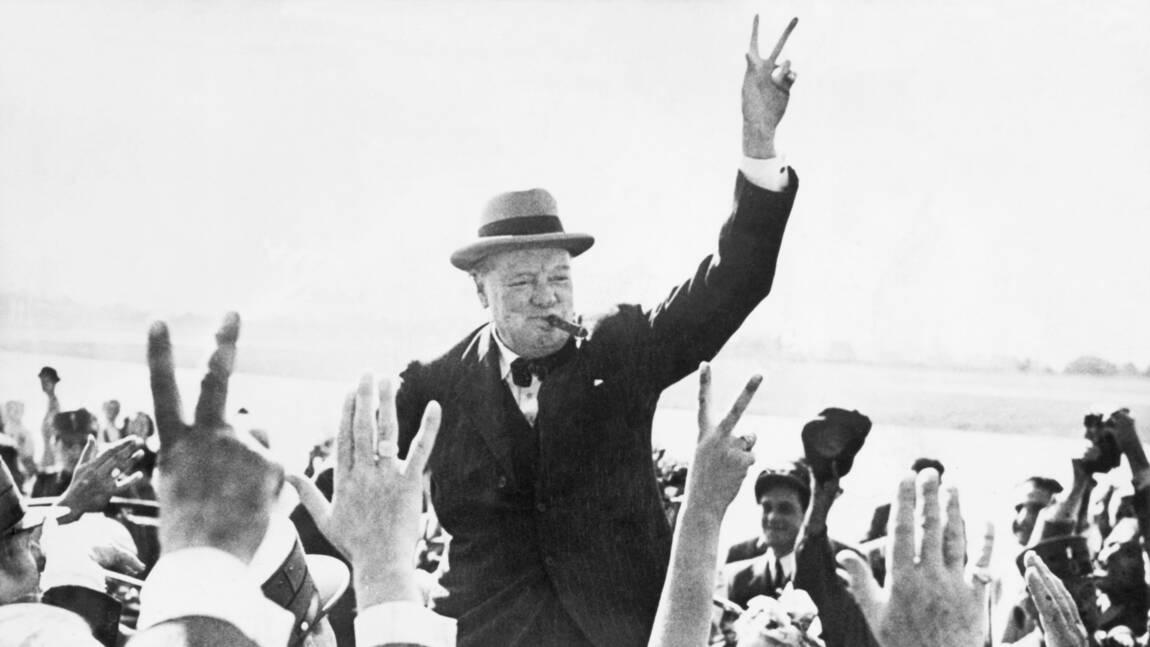 Winston Chruchill entouré par la foule levant les bras en faisant le V de la victoire. 