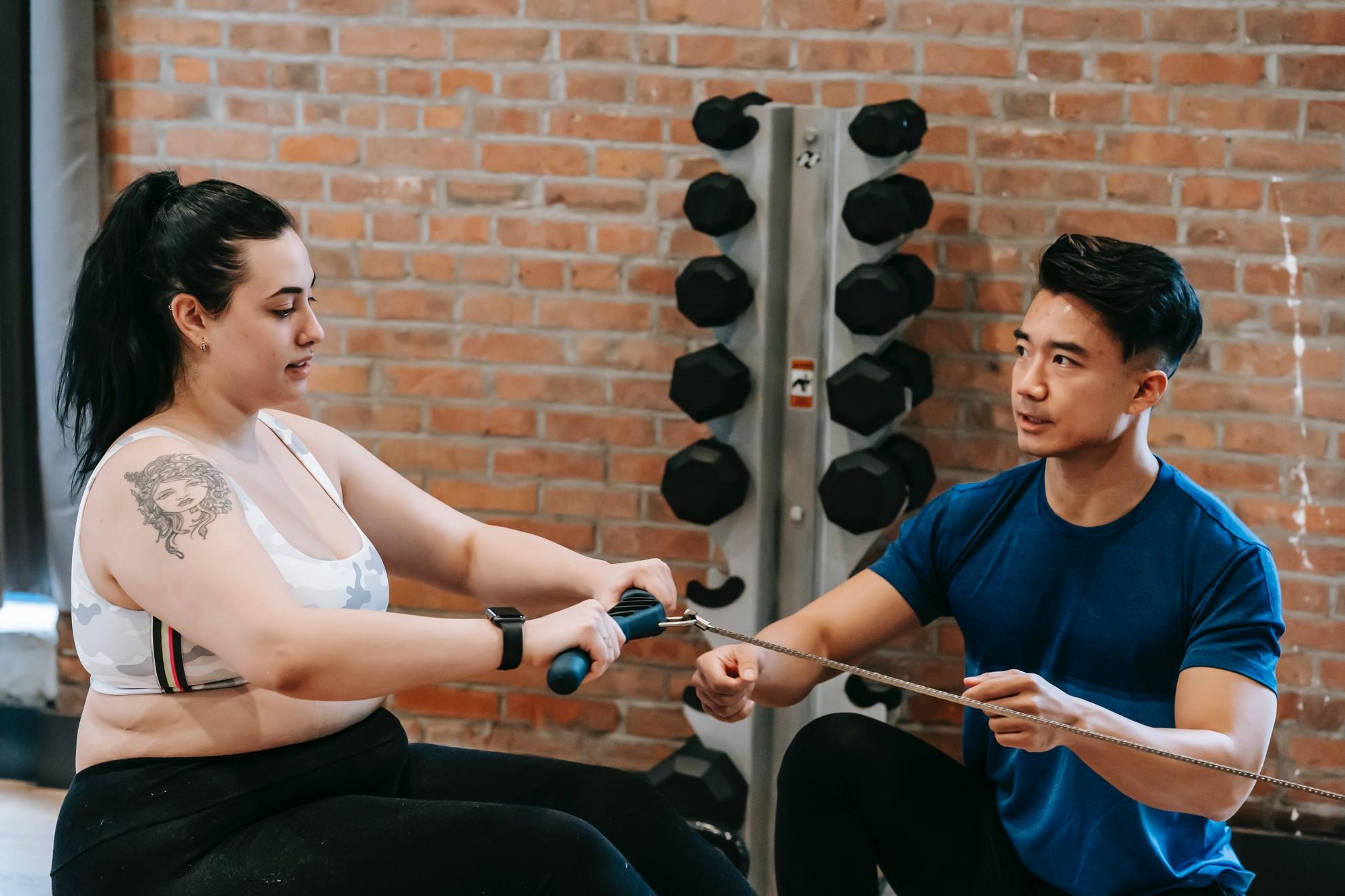 Un entraineur sportif et son élève en train de faire du rameur.