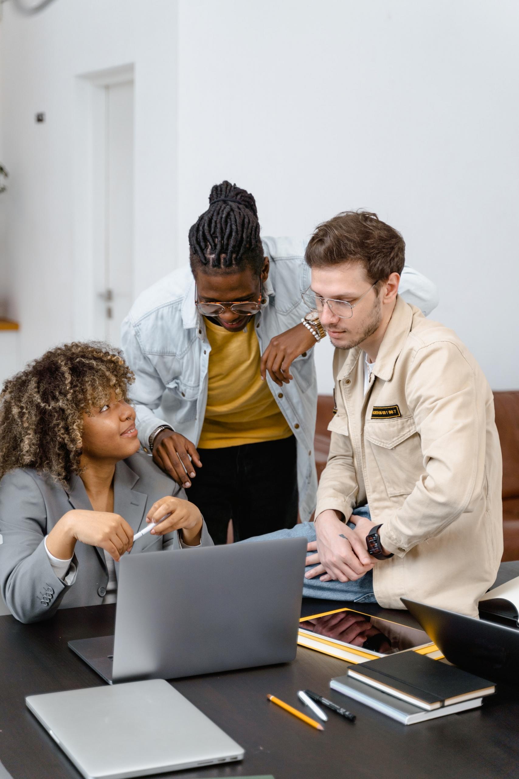 groupe de jeunes travailleurs qui réfléchissent ensemble autour d'un ordinateur portable