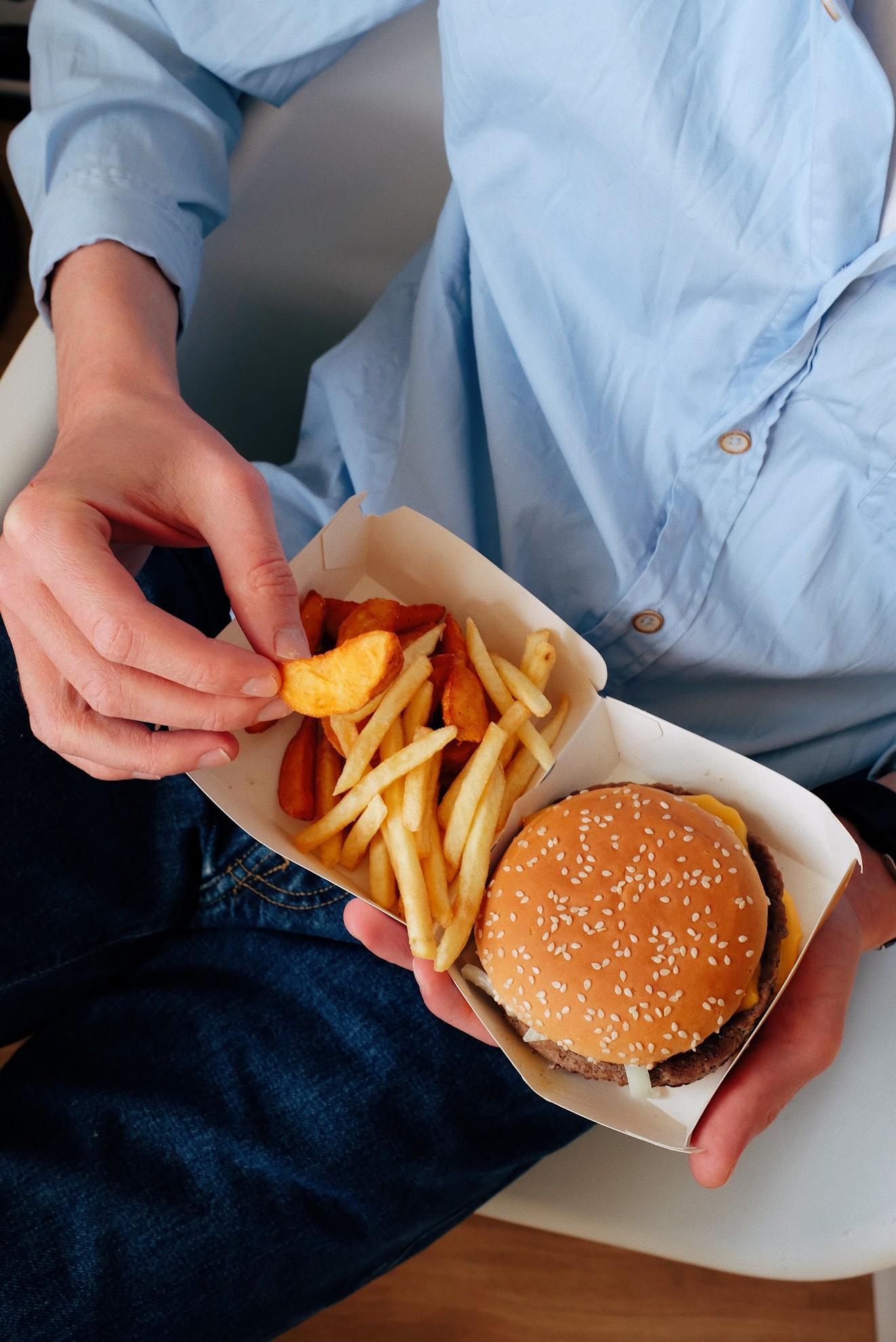 Un homme en train de manger un hamburger et des frites.