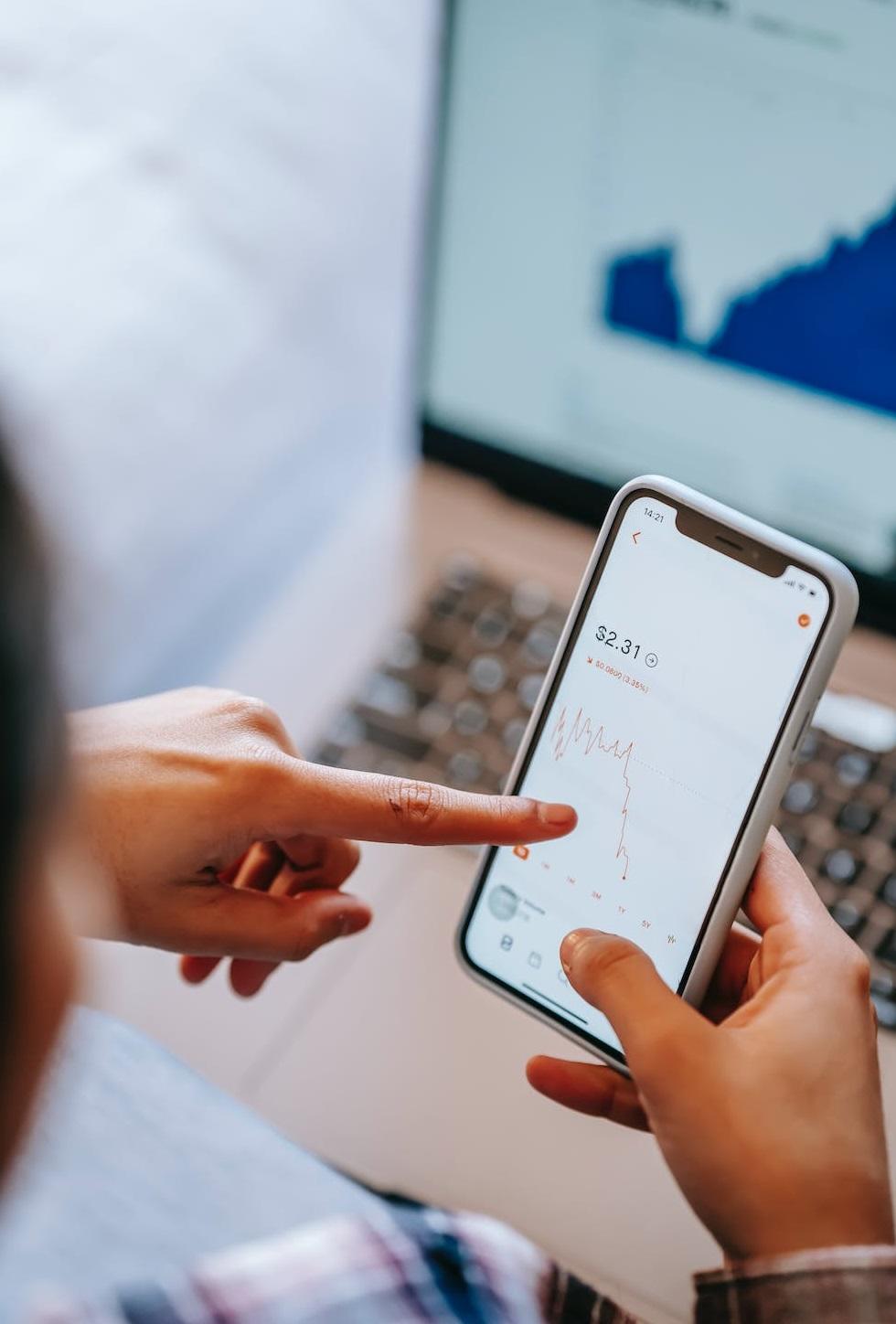 Une personne observe les flux économiques sur son smartphone. 