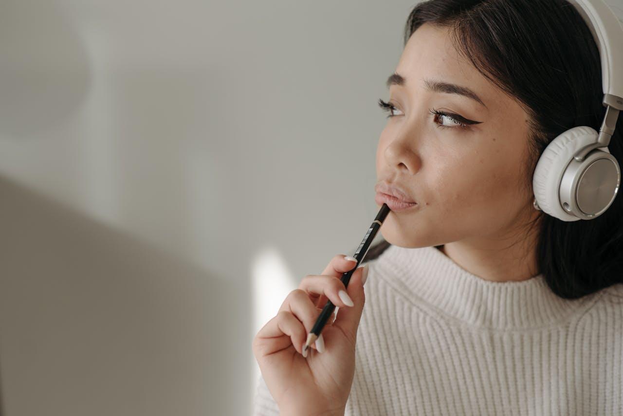 jeune femme avec son casque et un stylo concentree