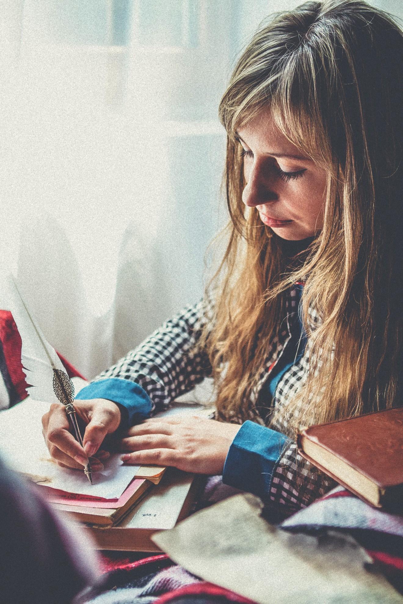 Une femme rédigeant un texte au stylo plume.