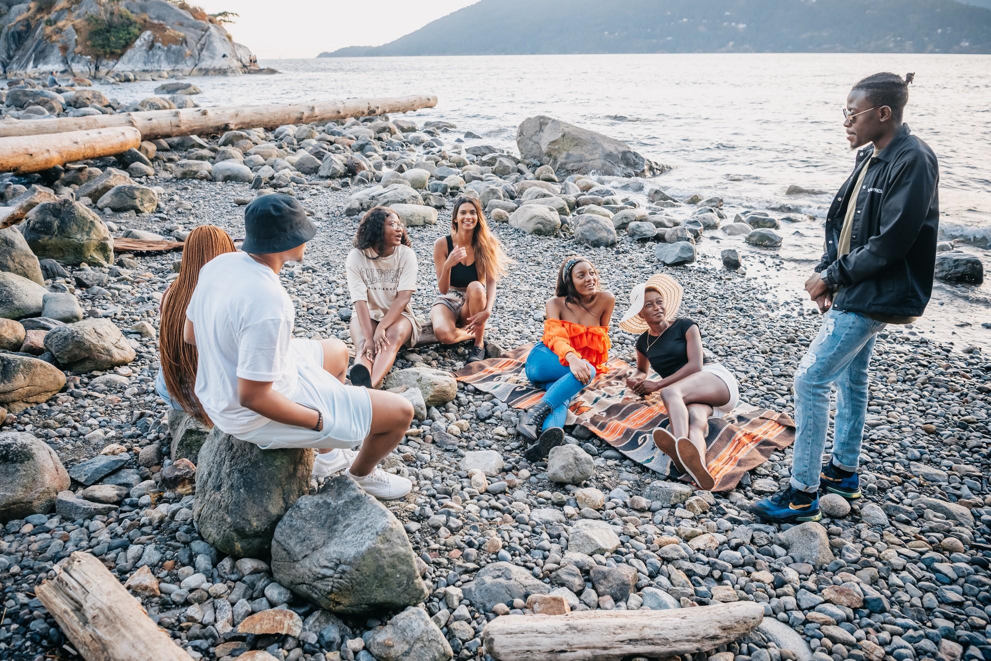 Un groupes de jeunes adultes en train de discuter sur une plage.