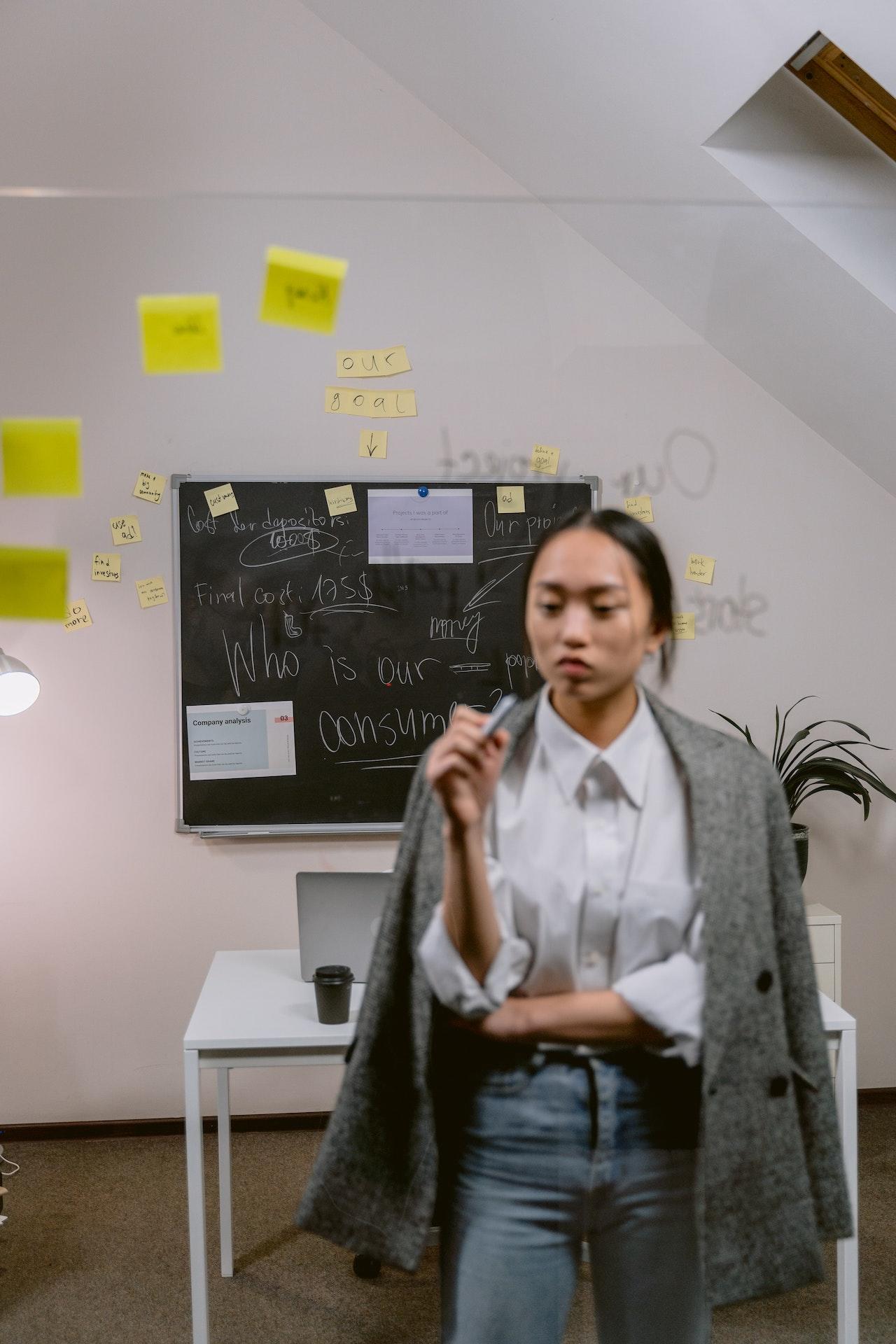 Jeune femme asiatique devant un tableau qui essaie d'apprendre l'alphabet coréen.