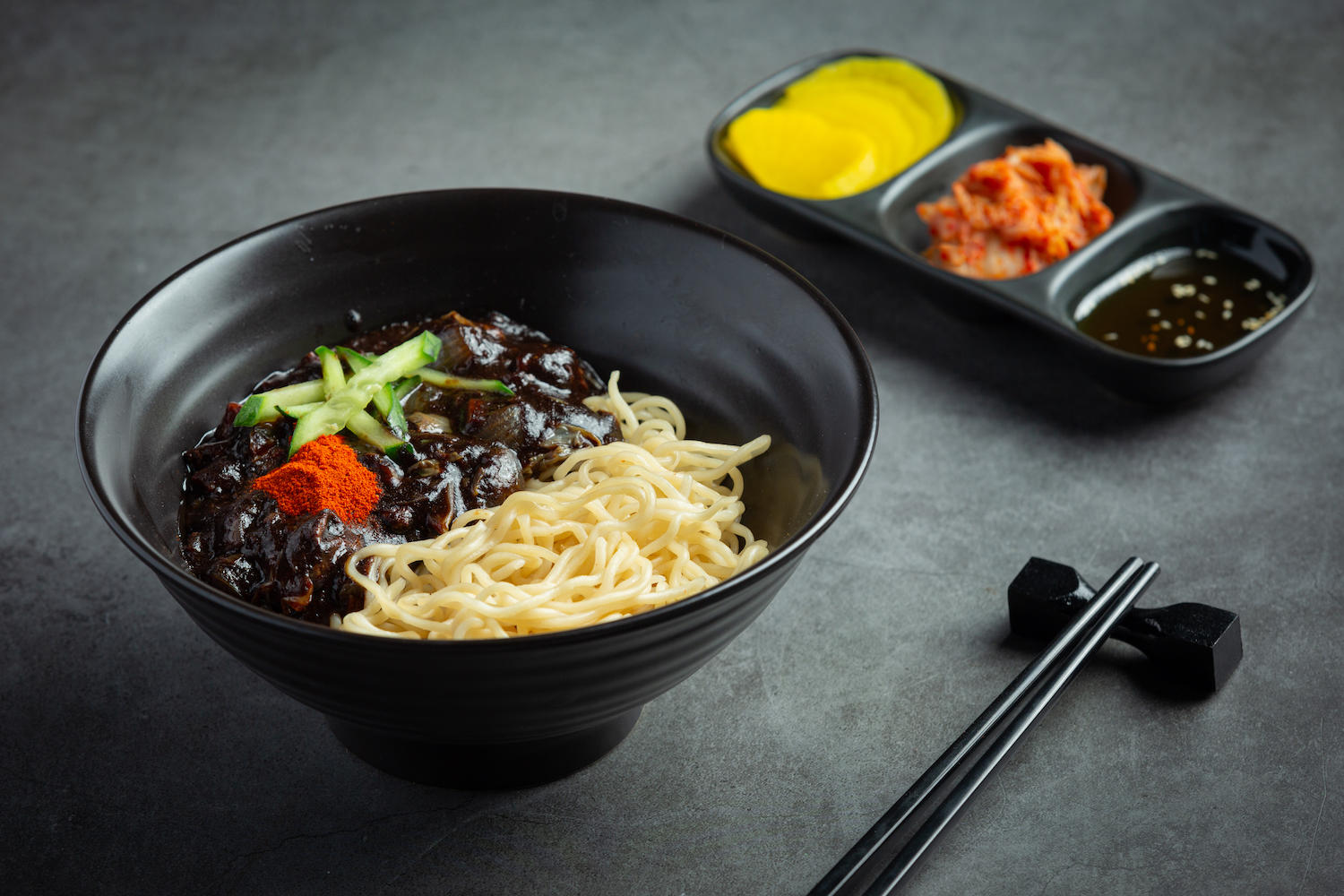 Bol avec nouilles et haricots fermentés, petit plat de sauce en arrière-plan.