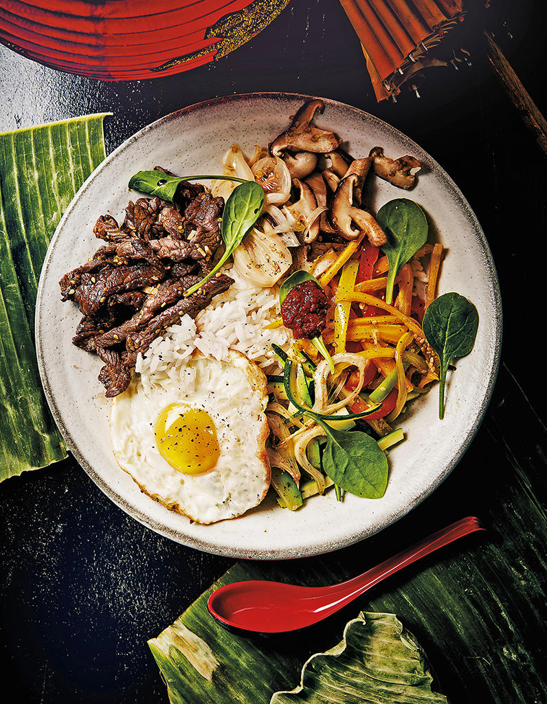 Plat avec du boeuf, des nouilles, des légumes et un oeuf présenté dans une assiette.