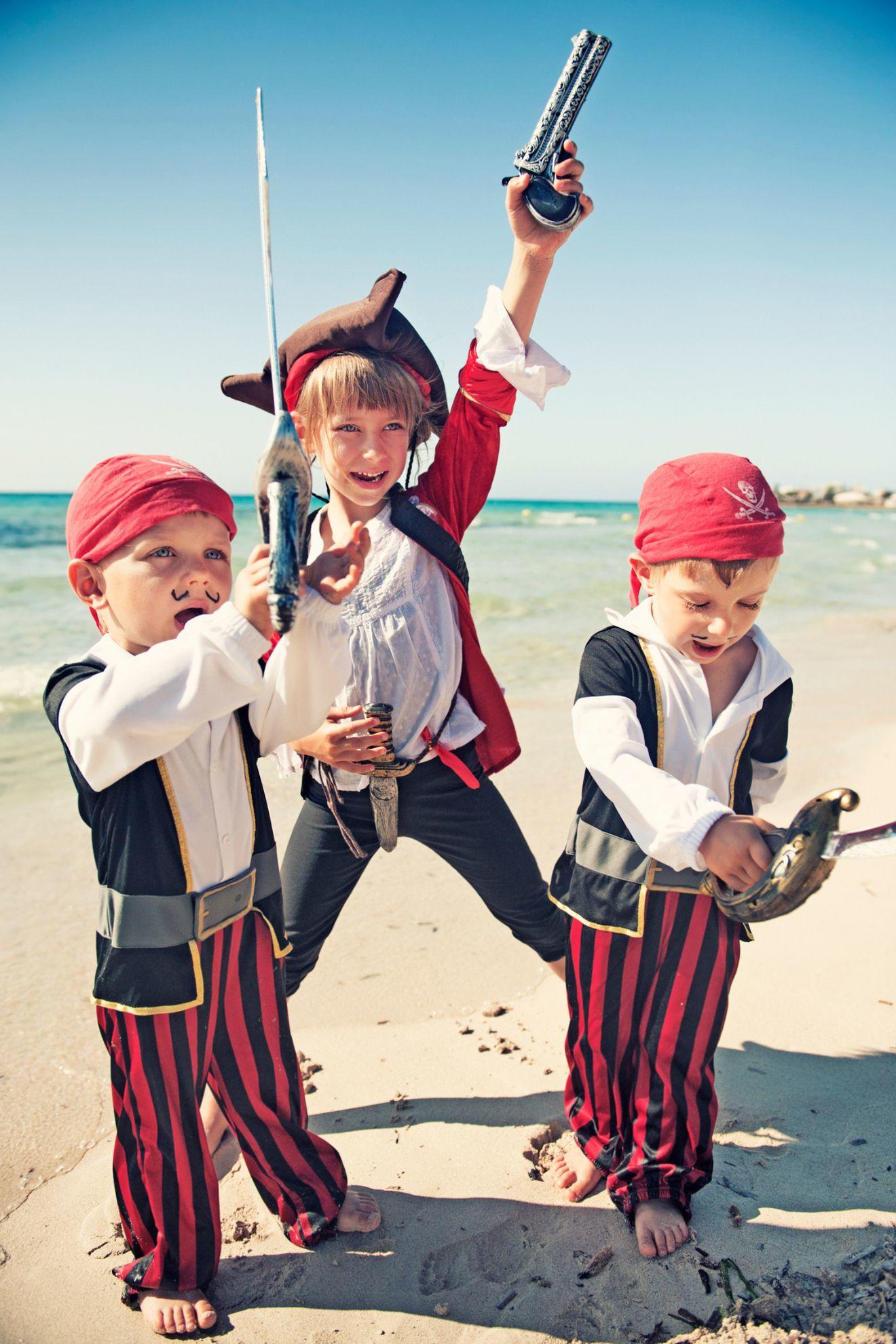 Des enfants déguisés en pirate qui jouent sur la plage.