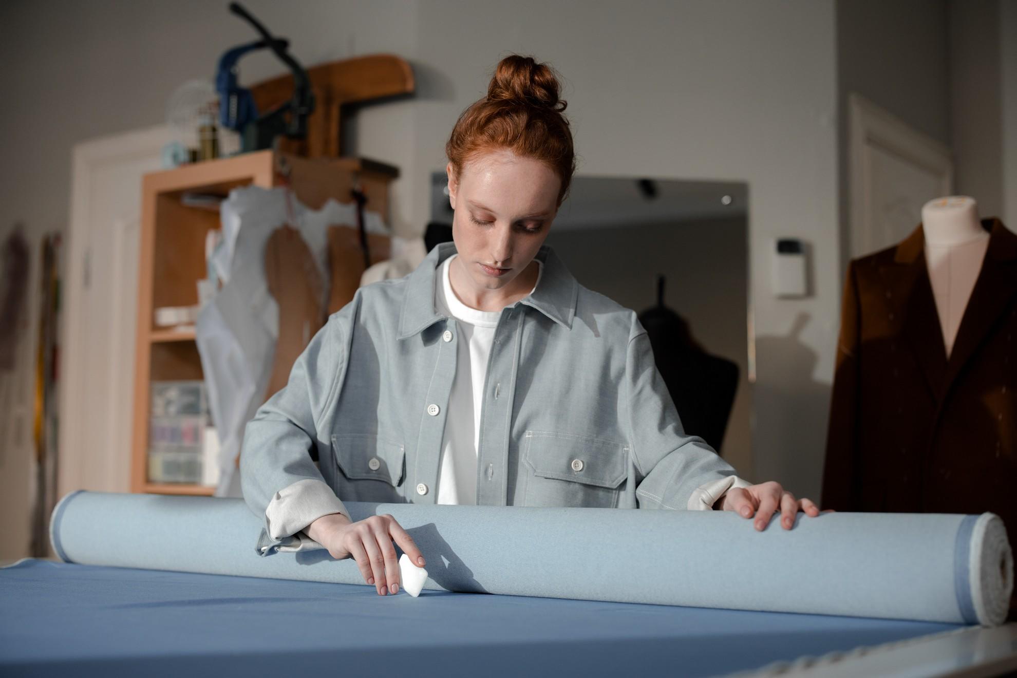 Une femme en train de marquer sa pièce de tissu à la craie blanche.