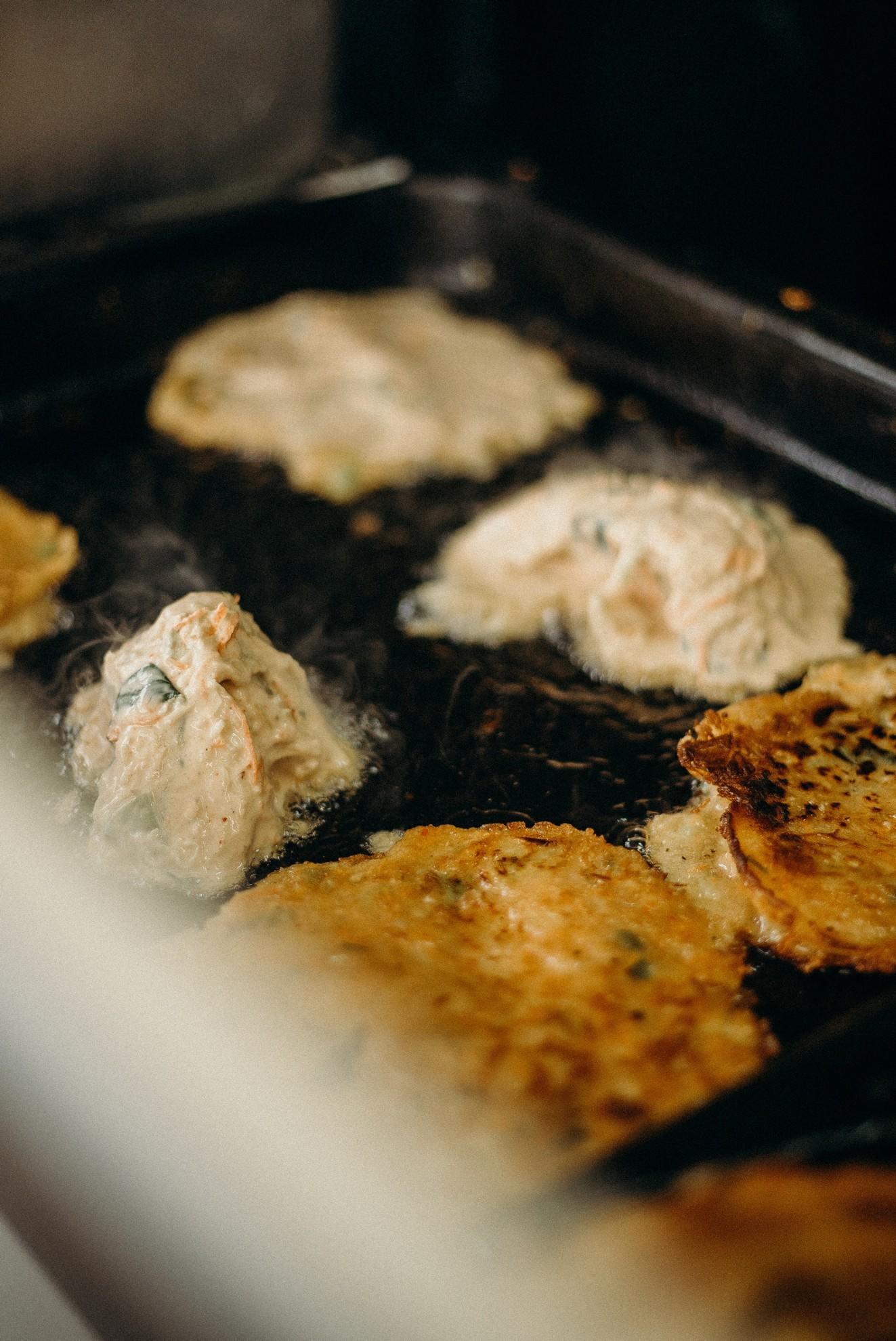 Un grill où cuisent des galettes de légumes.
