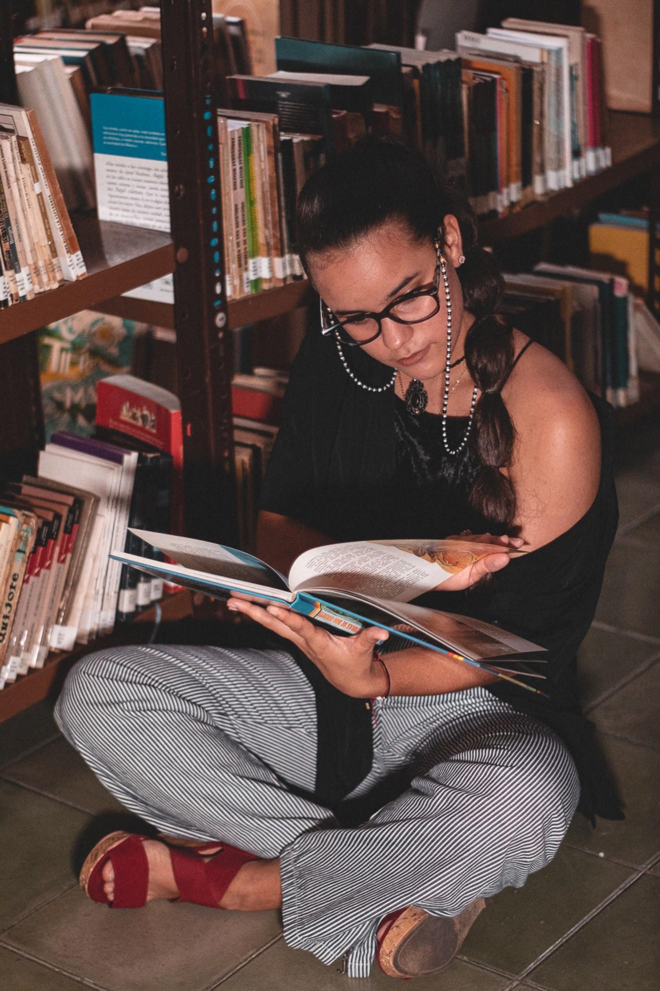 Une femme assise dans le rayon d'une bibliothèque.