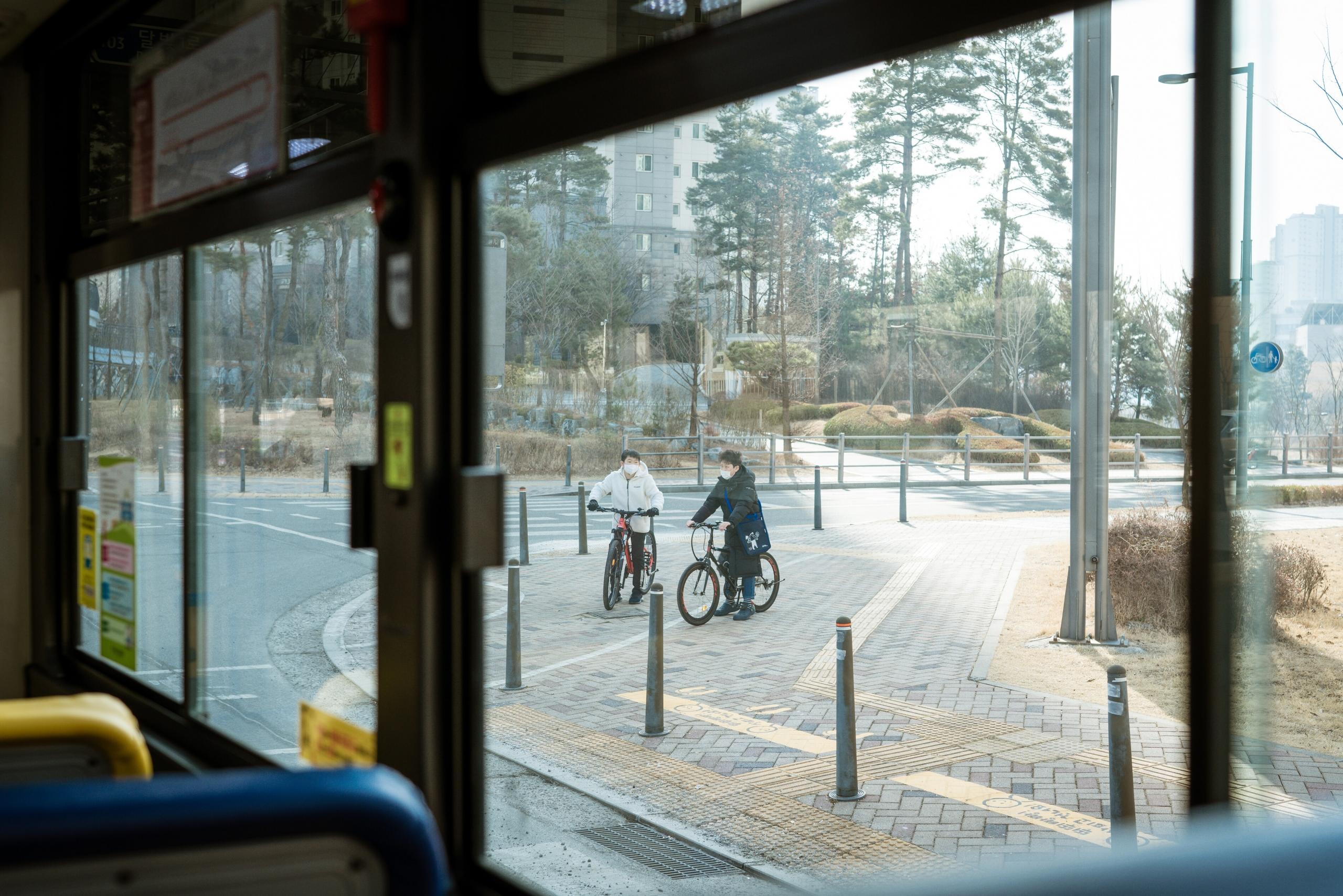À travers la vitre du bus, des vélos roulent en Corée
