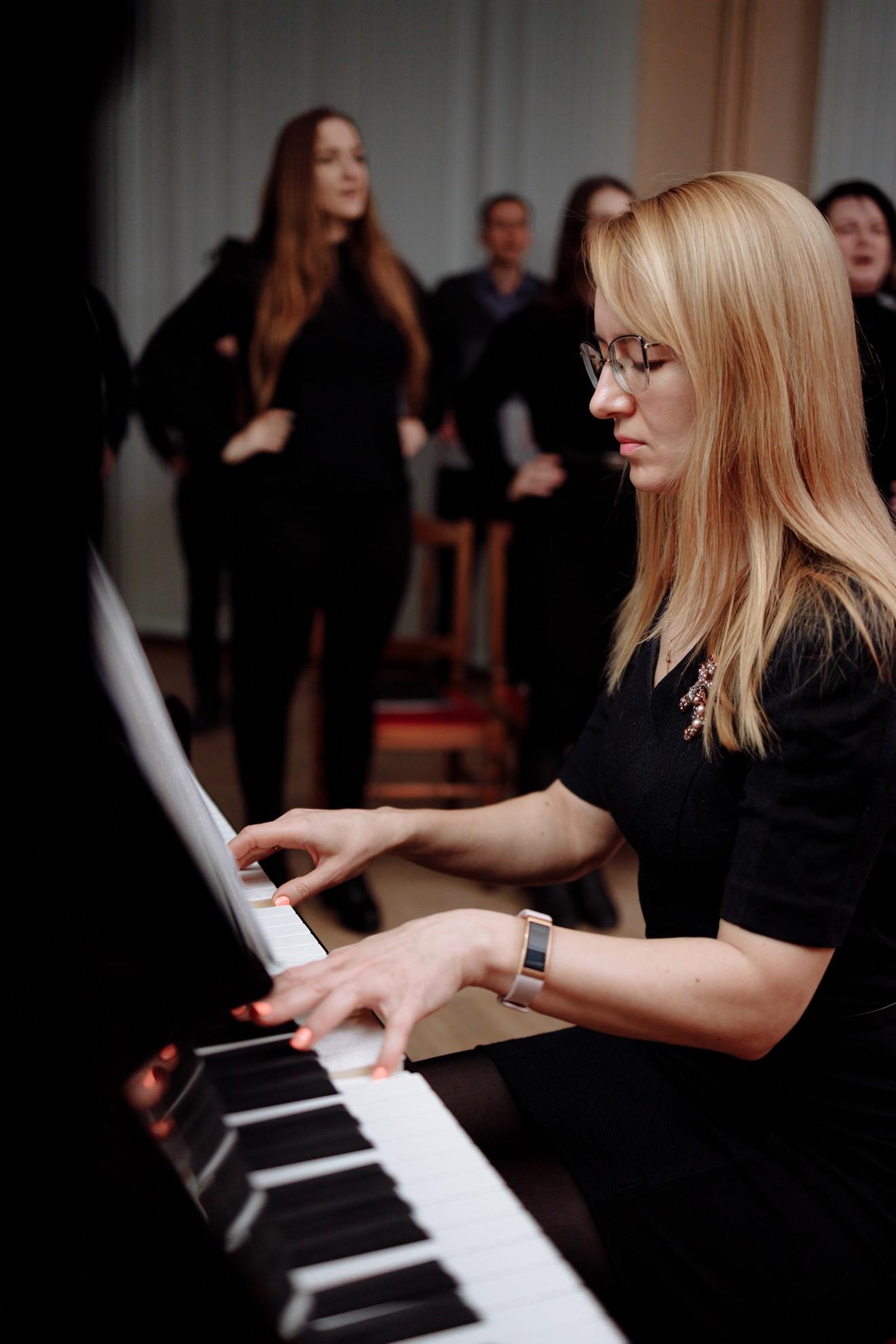 Une jeune femme jouant du piano devant d'autres musiciens.